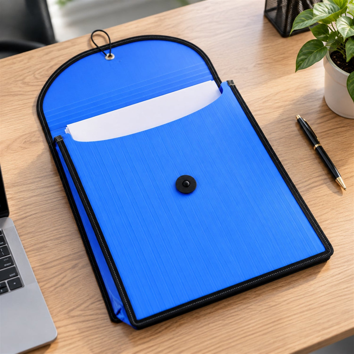 An open blue plastic document folder with white papers inside, lying on a wooden desk next to a laptop and pen.