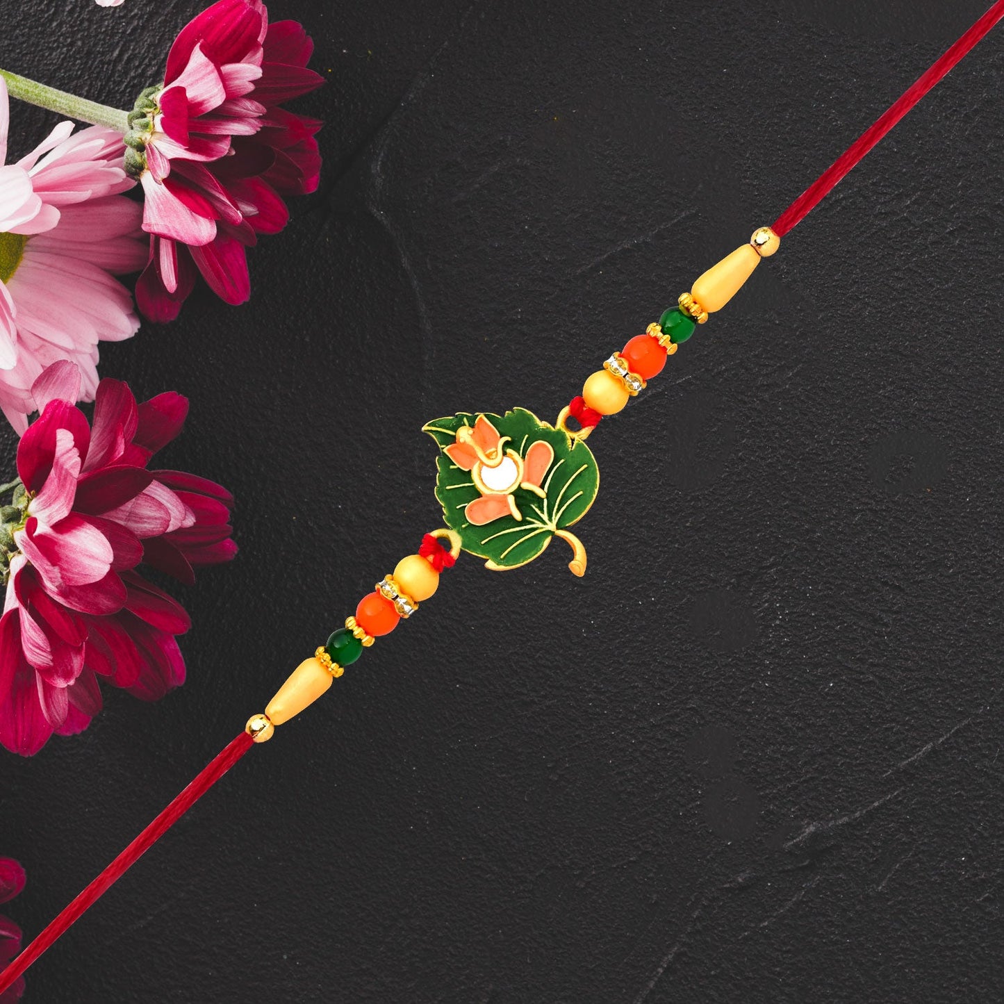 Close-up of Green Tulsi Rakhi with orange enamel flower