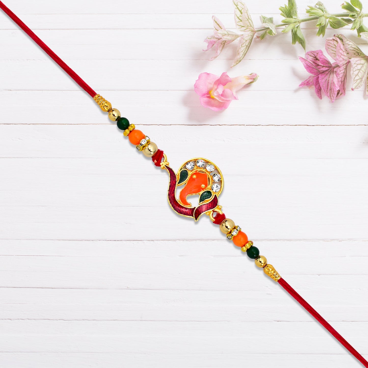 Hand holding golden Ganesha Rakhi featuring vibrant beads and intricate stone detailing