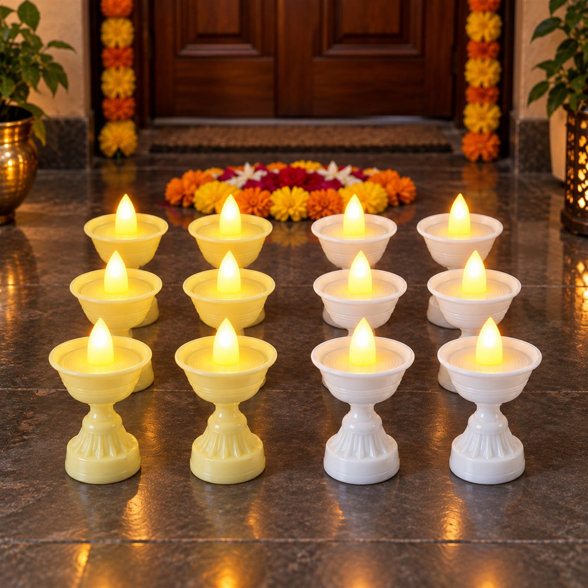 Twelve LED diya candles, six yellow and six white, are arranged on a dark tiled floor in front of a decorated doorway.