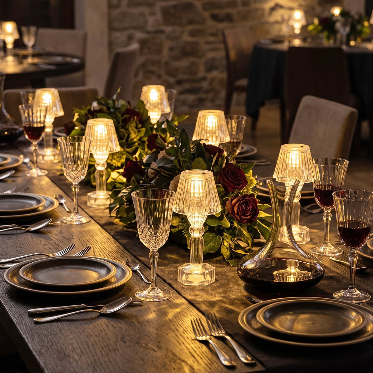 An elegant dining setting featuring many clear acrylic LED lamps emitting warm light on a long wooden table.