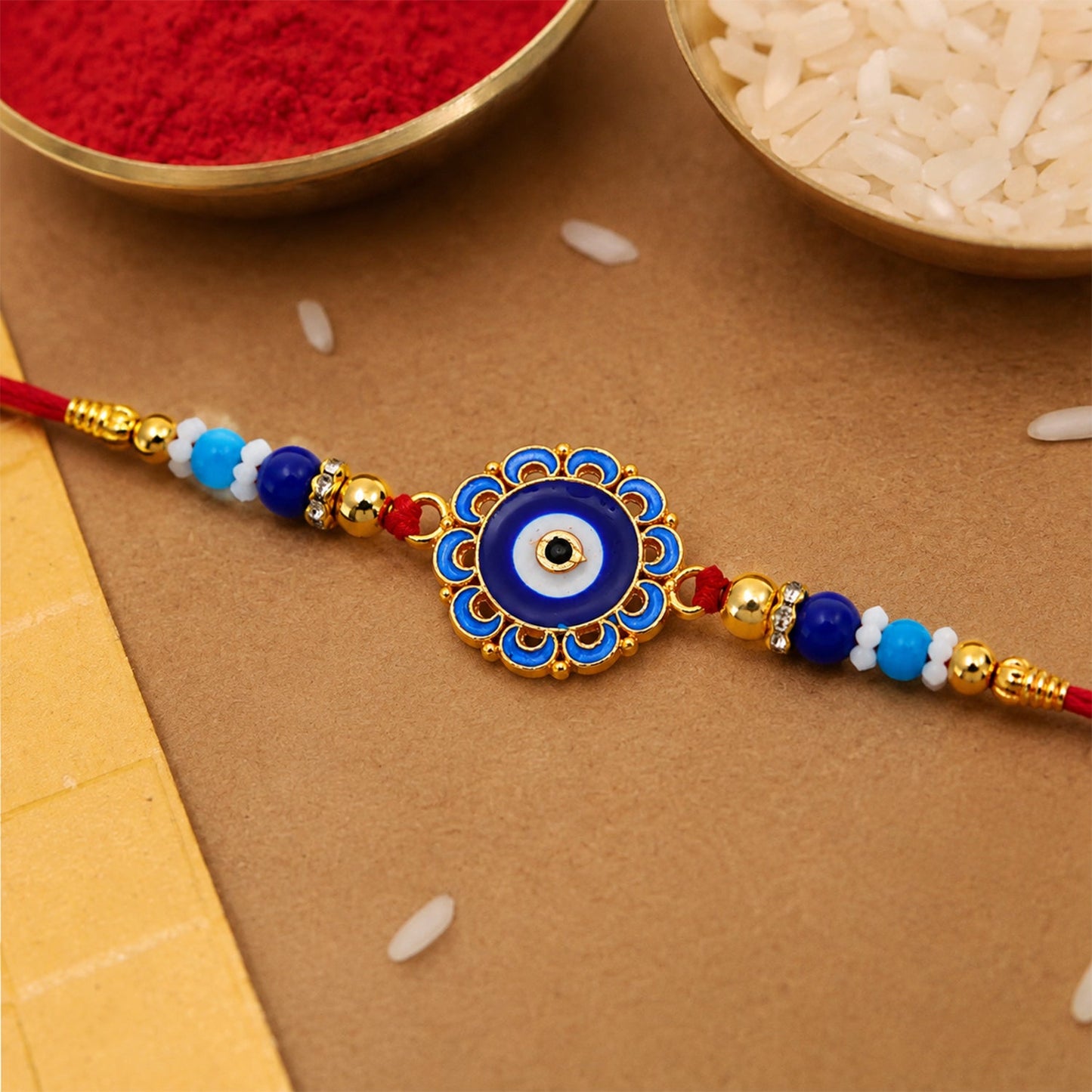 Close-up of an Evil Eye Rakhi with blue beads and golden accents, ready for Raksha Bandhan.