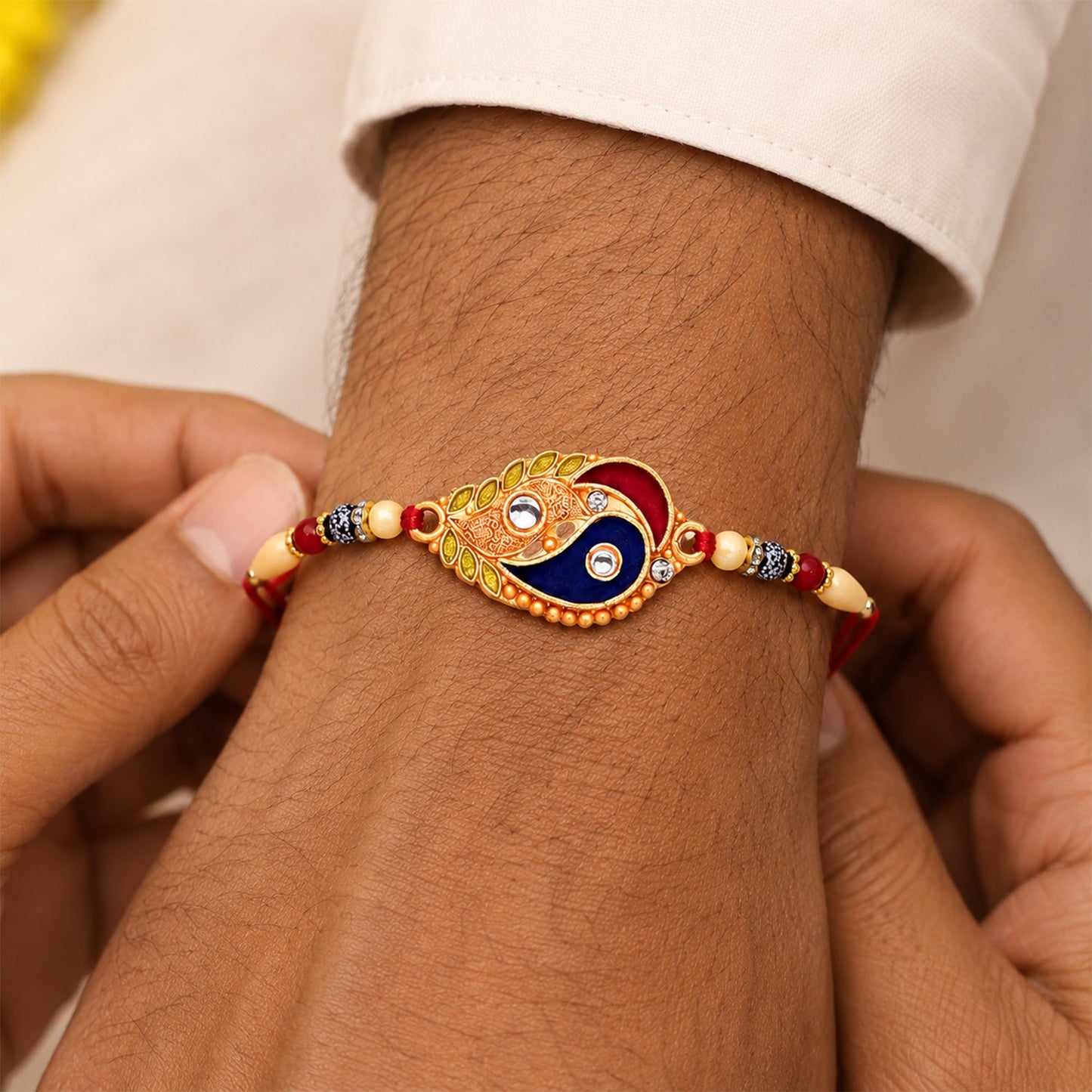 Close-up of enamel paisley rakhi showing gold-tone accents and artistic craftsmanship
