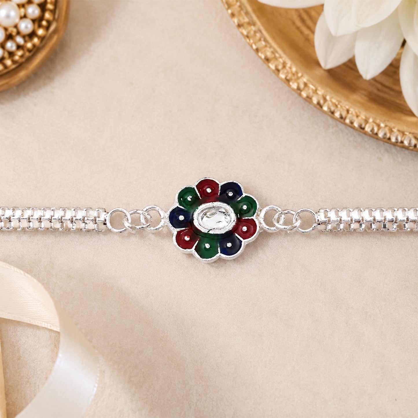 Silver chain detail holding colorful petal Rakhi for sibling celebration