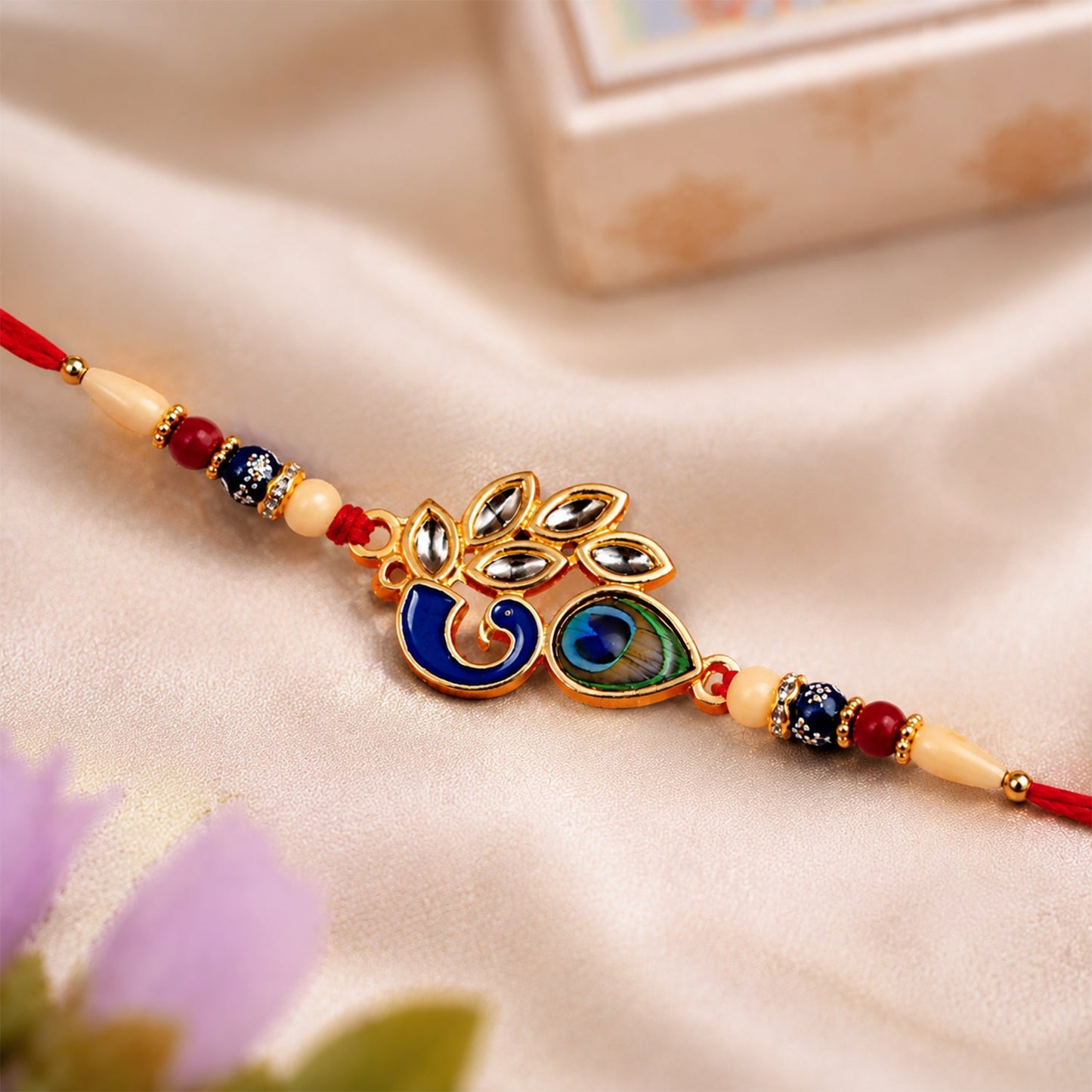 Artistic Mor Pankh Rakhi worn on wrist showcasing colorful enamel and red thread