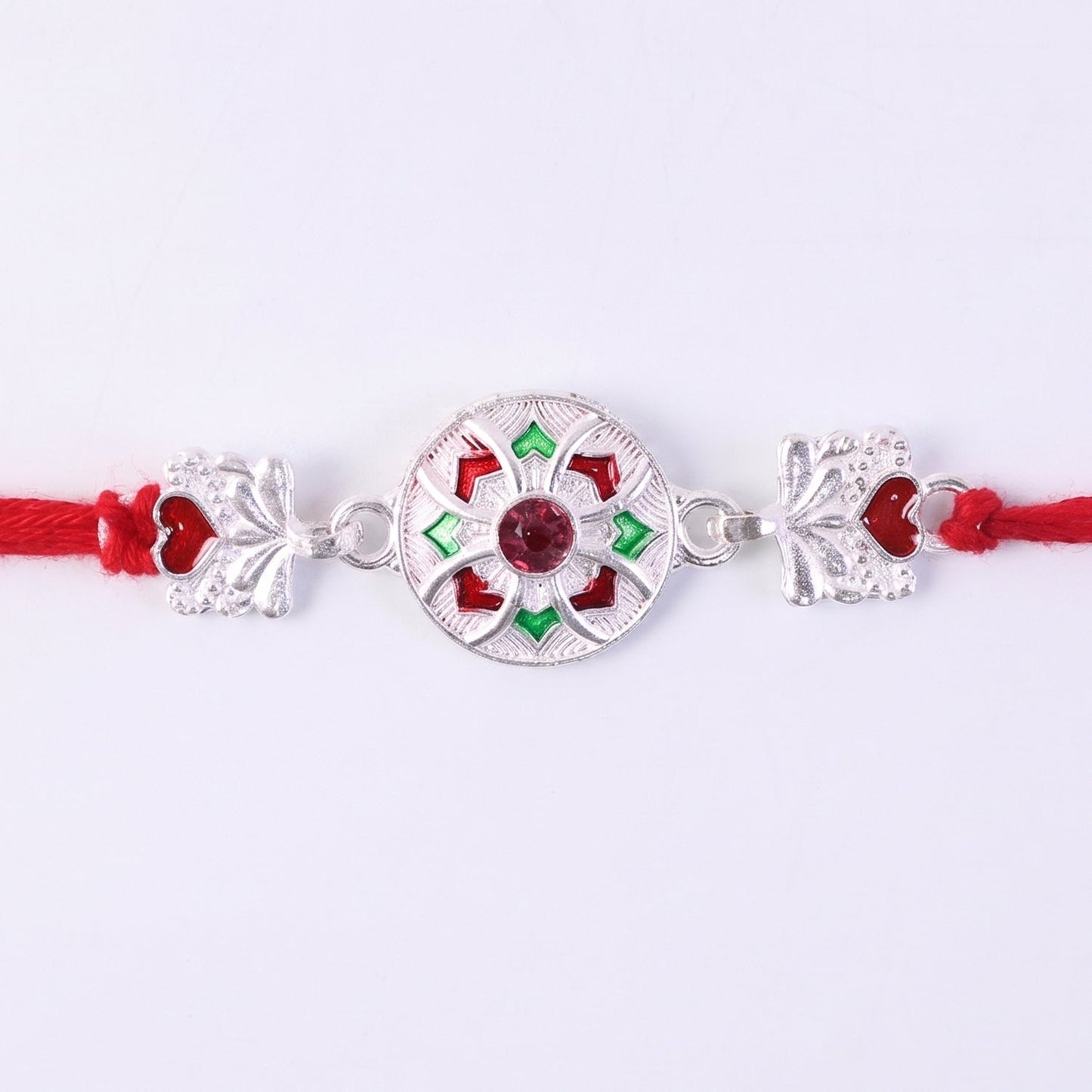 Elegant silver rakhi with red and green decorative elements on metallic base