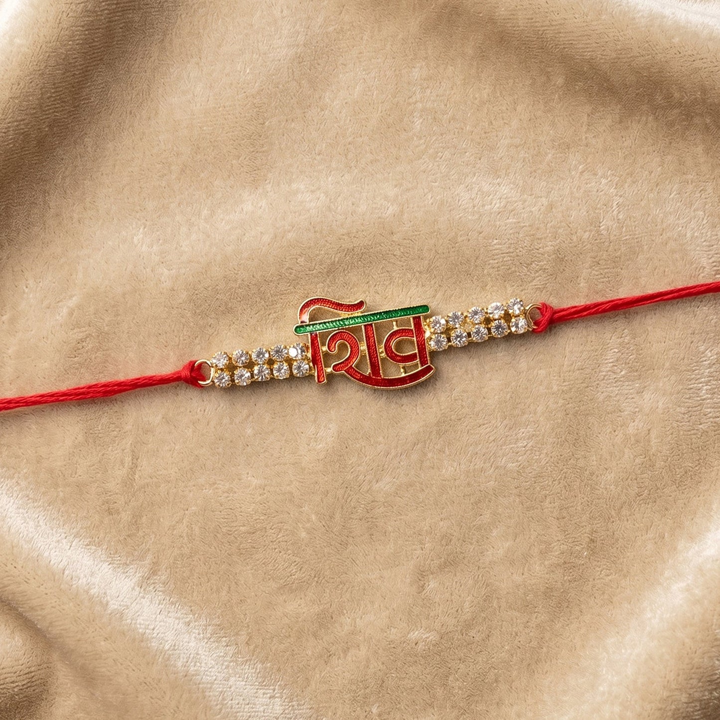 Close-up of Shiv letter rakhi with red Mauli thread and crystals