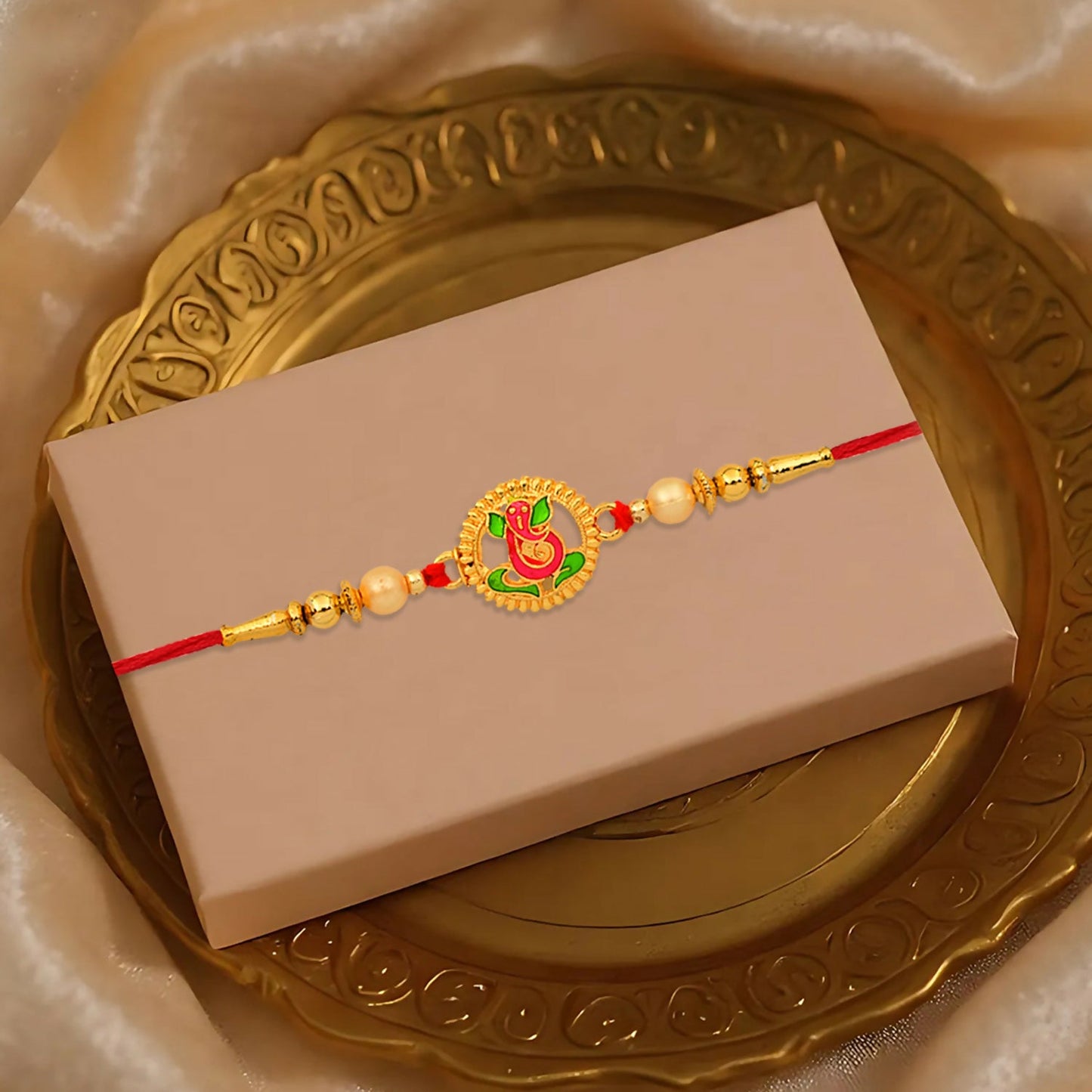 Close-up of Ganesha Rakhi featuring colorful enamel and golden beads