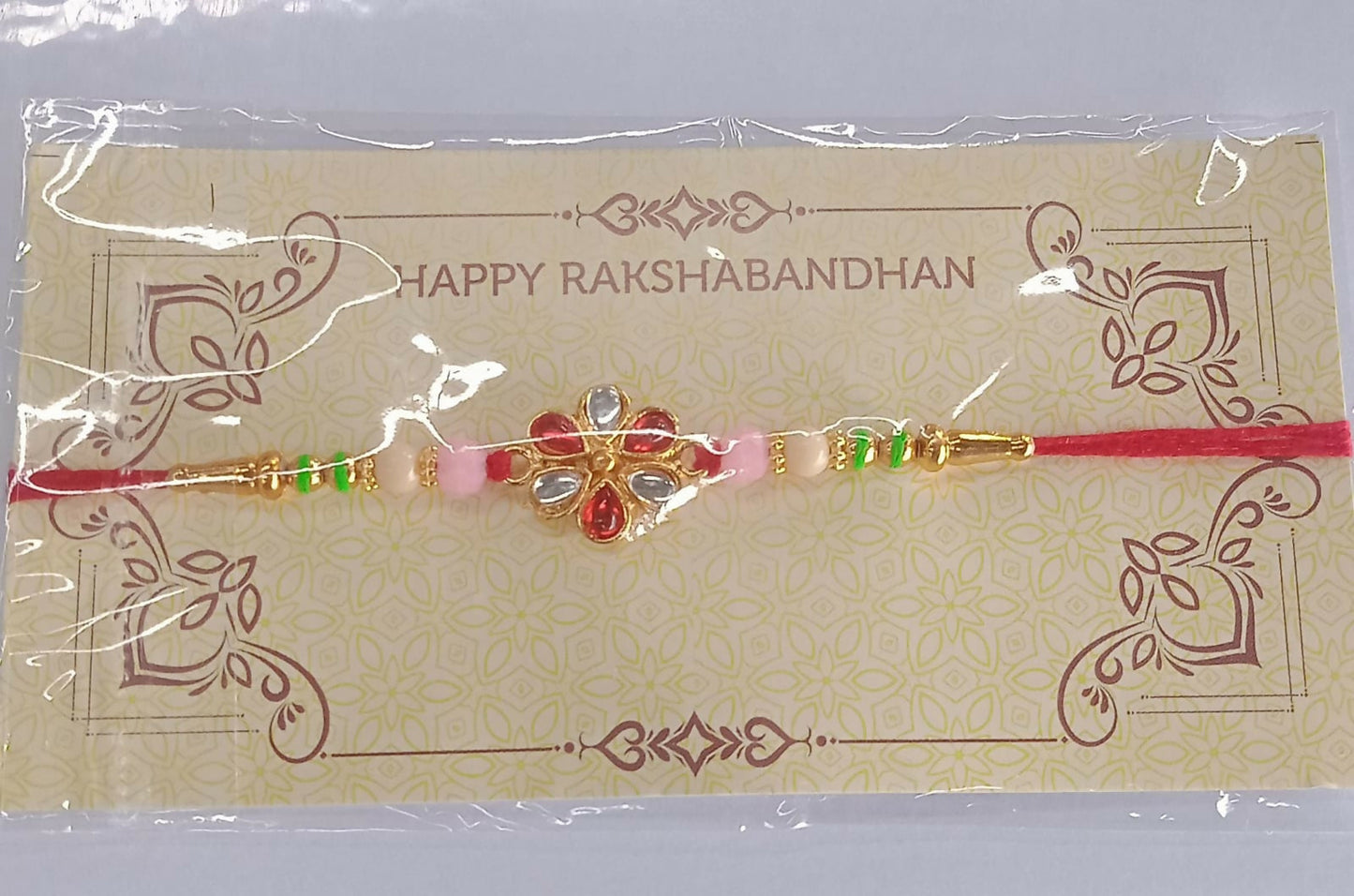 Artistic image of red white beaded Rakhi featuring detailed Kundan floral centerpiece