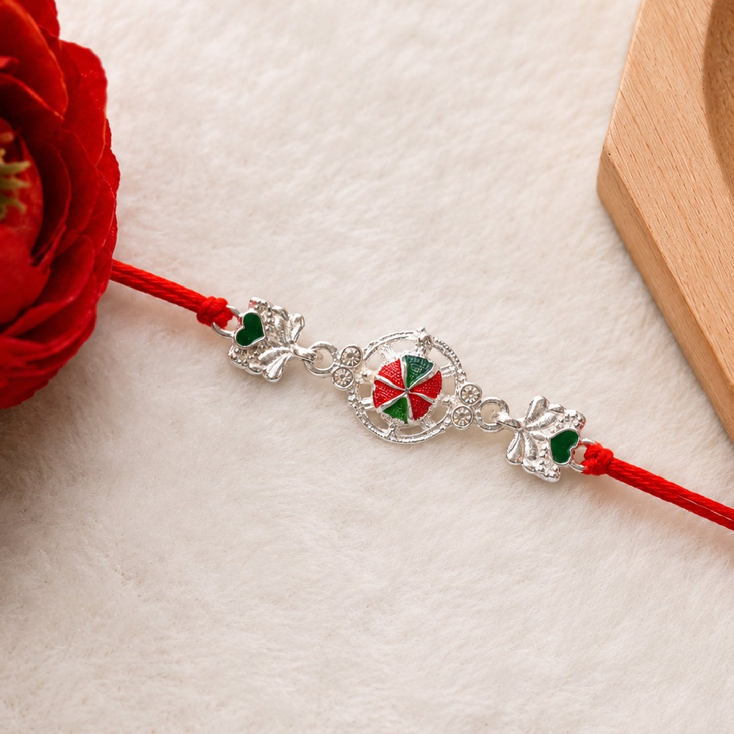Top view of Silver Floral Rakhi showing soft red thread
