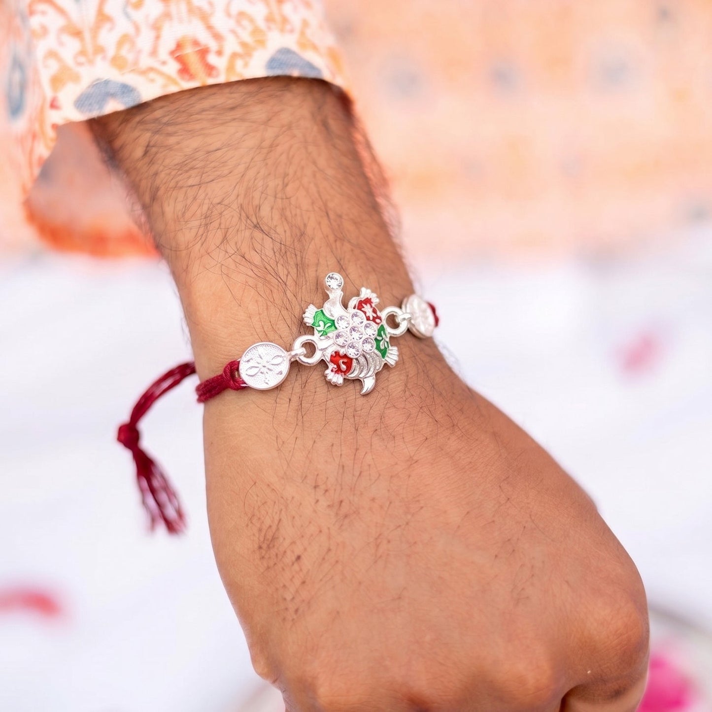 Close-up of colorful enamel and floral centerpiece on rakhi