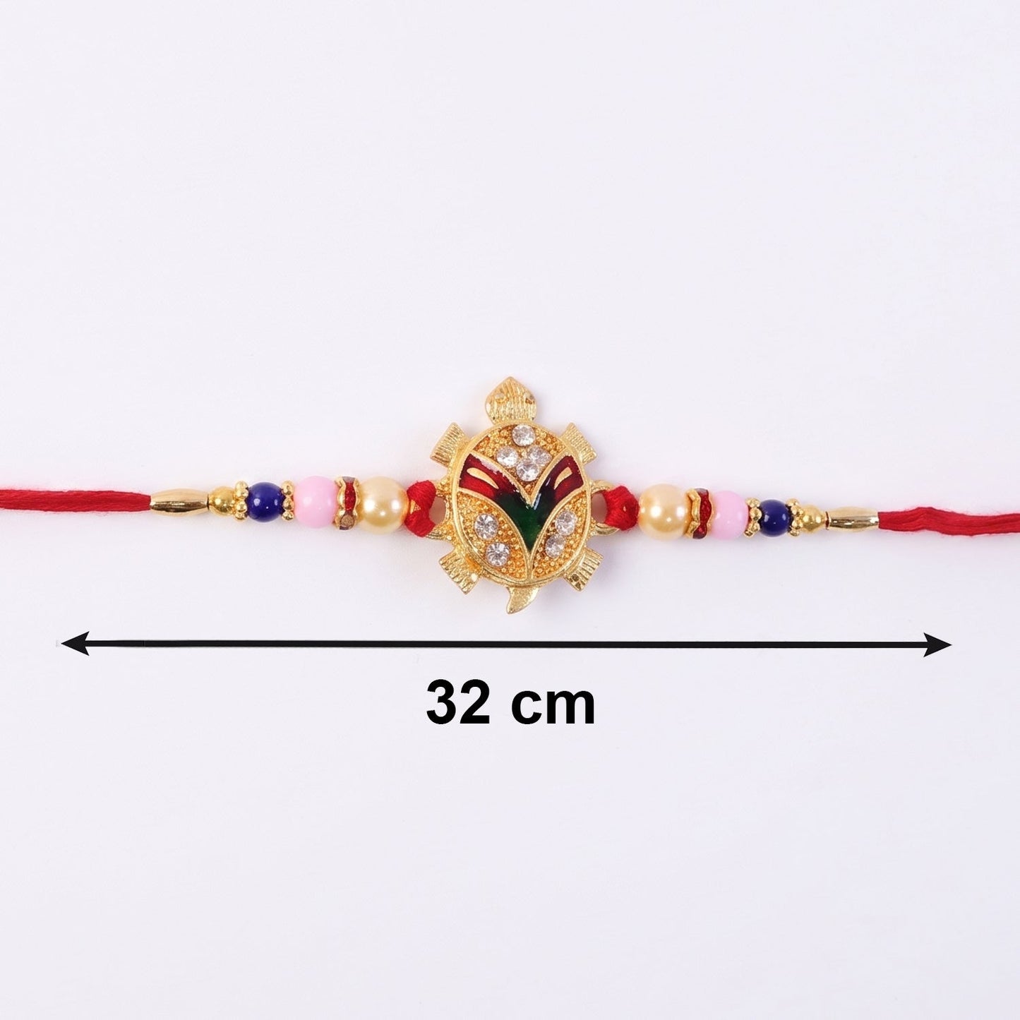 Hand holding golden turtle Rakhi with decorative beads