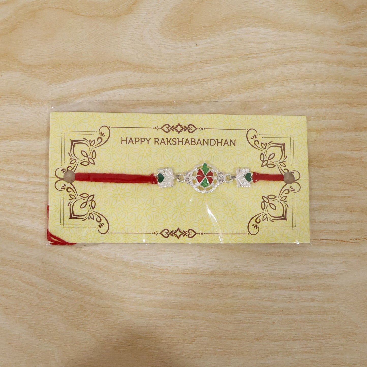 Silver floral Rakhi tied with red thread on wrist