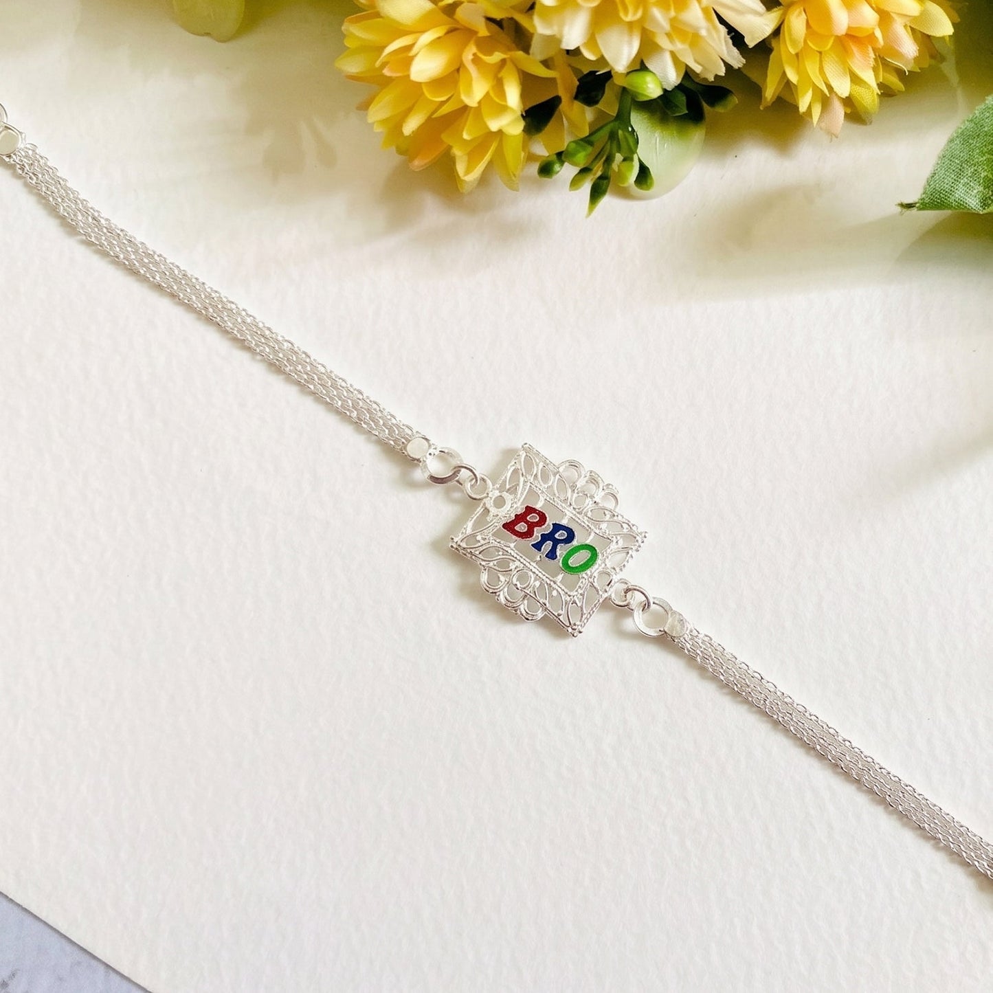 Close-up shot revealing the fine craftsmanship of the square frame on the Silver Rakhi.