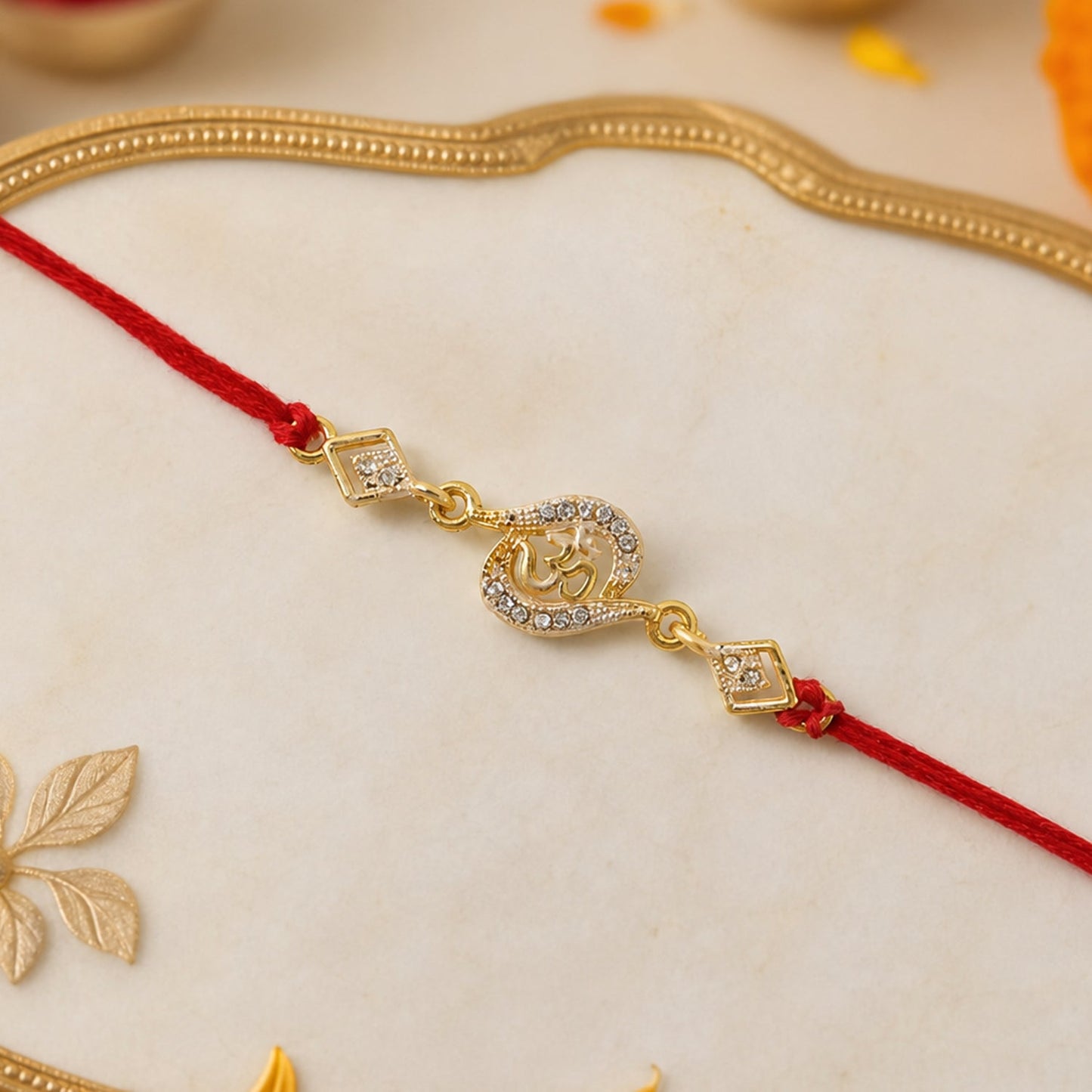 Close-up of Om symbol on Rakhi with stone work and red thread
