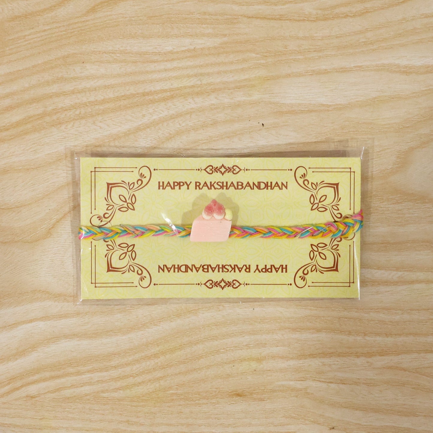 Side angle view of Strawberry Cake Charm Fancy Dori Rakhi for brother