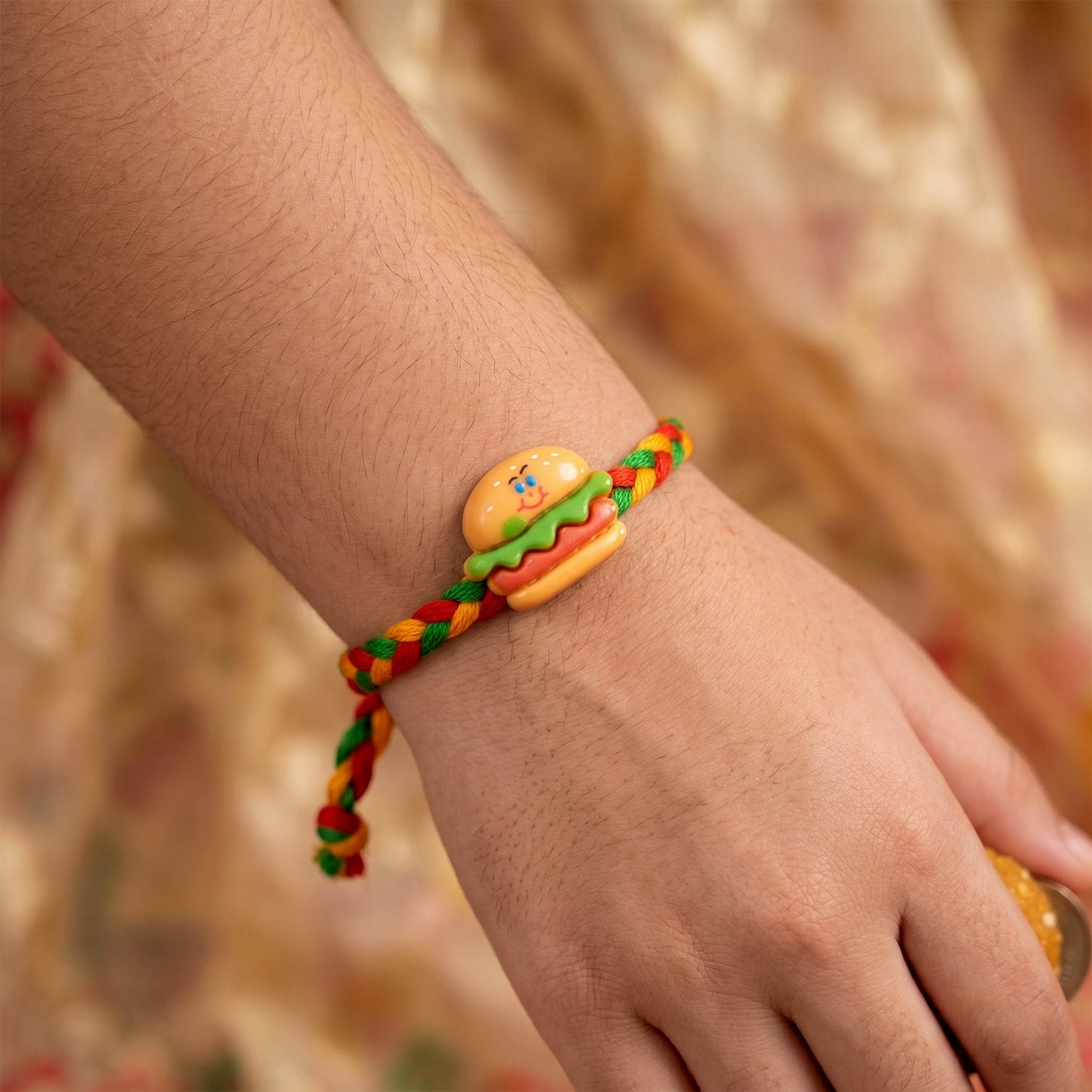Side view of Burger Charm Rakhi showcasing its intricate Dori thread.