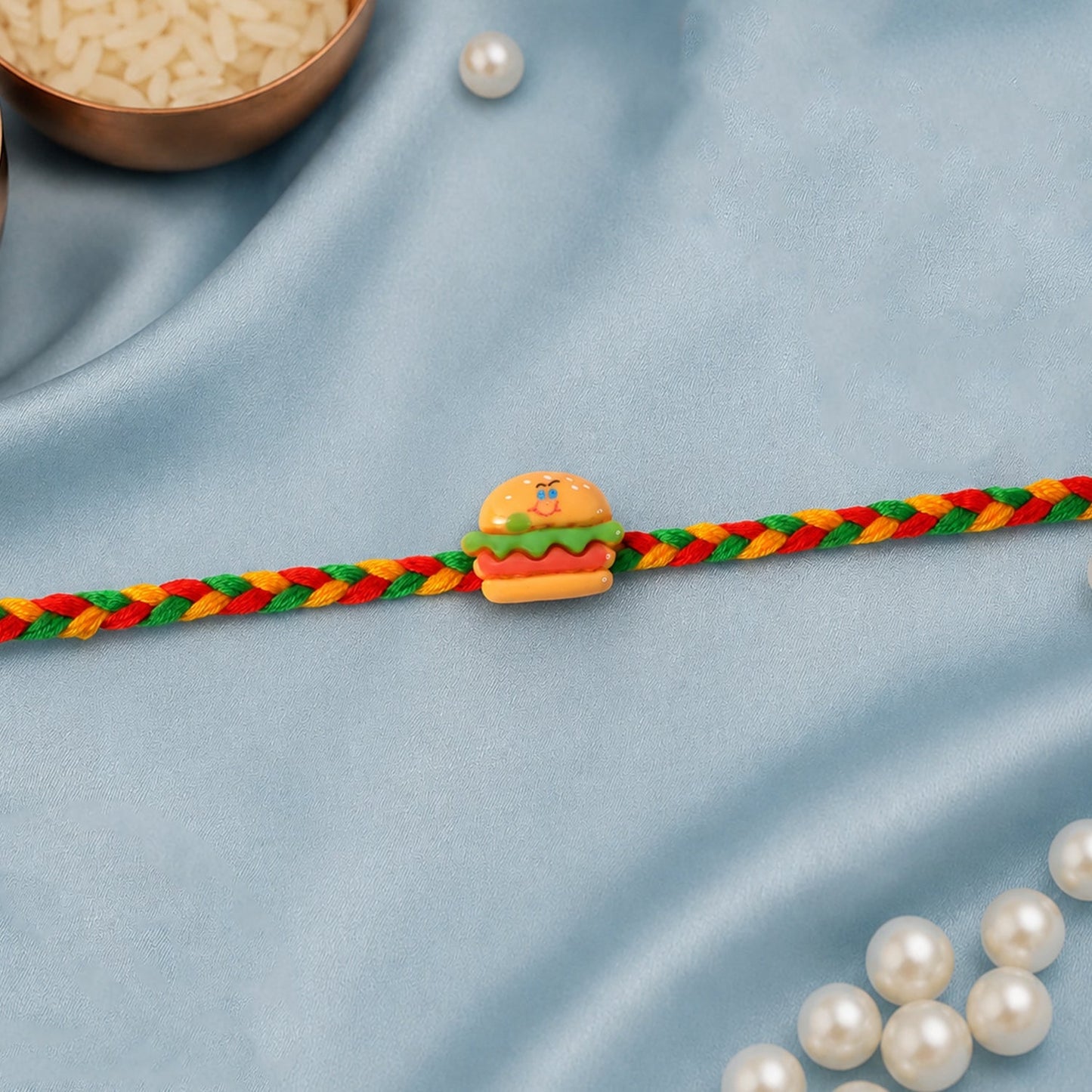 Close-up of the detailed burger charm on the Rakhi.