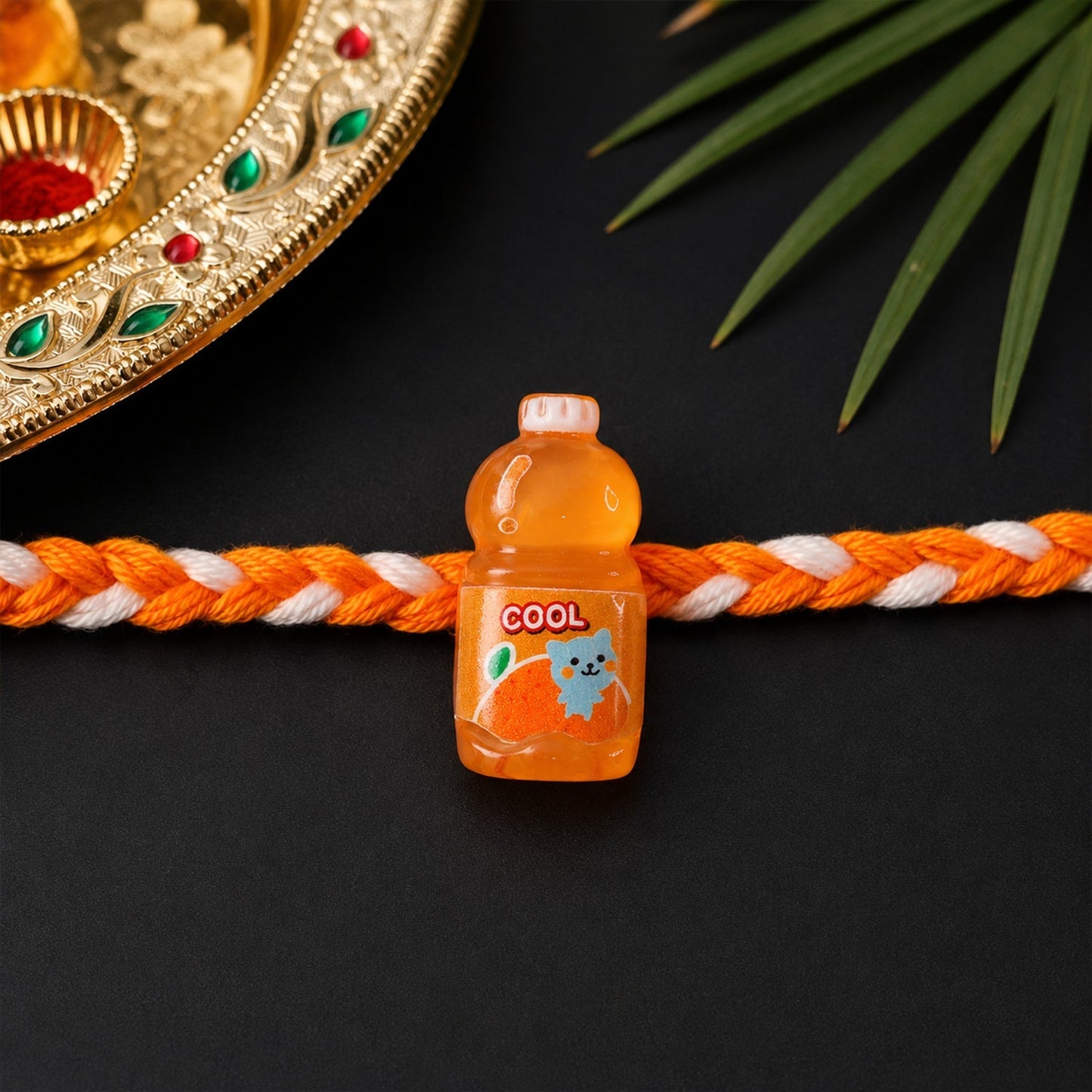 Close-up of fancy drink bottle charm rakhi with detailed design