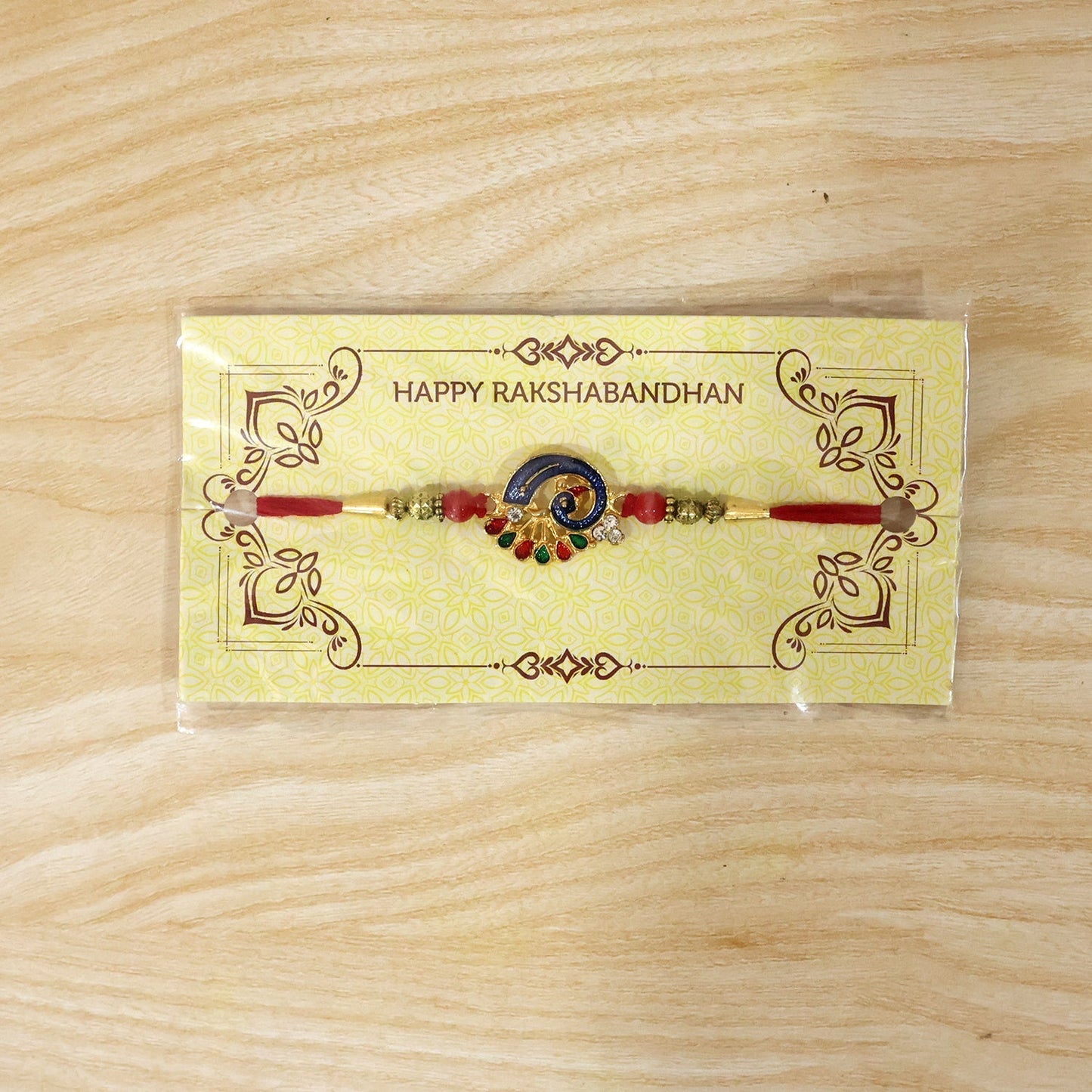 Colorful Peacock Charm Rakhi with red beads tied on string