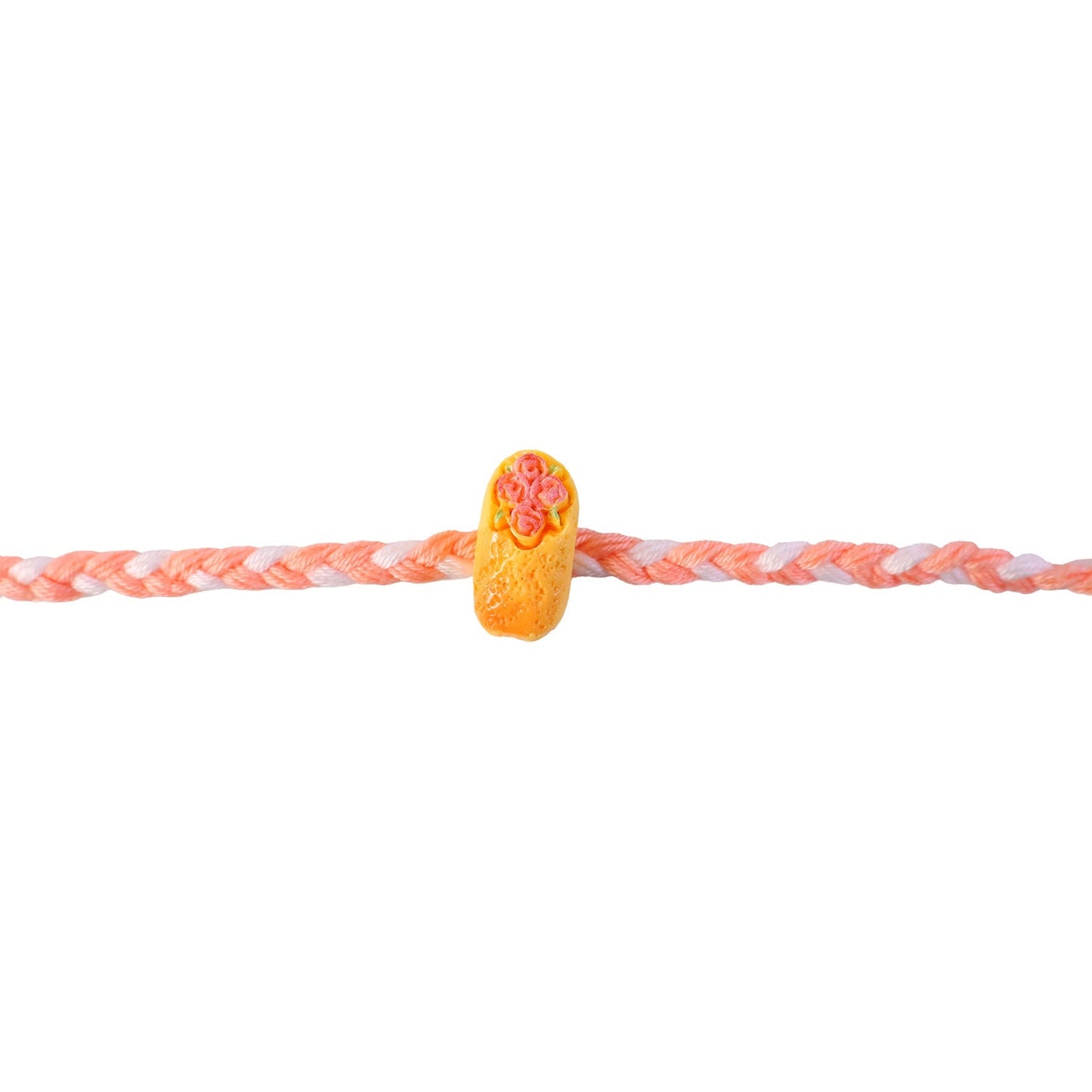 Cake charm Rakhi with braided thread, ready to be tied for Raksha Bandhan.