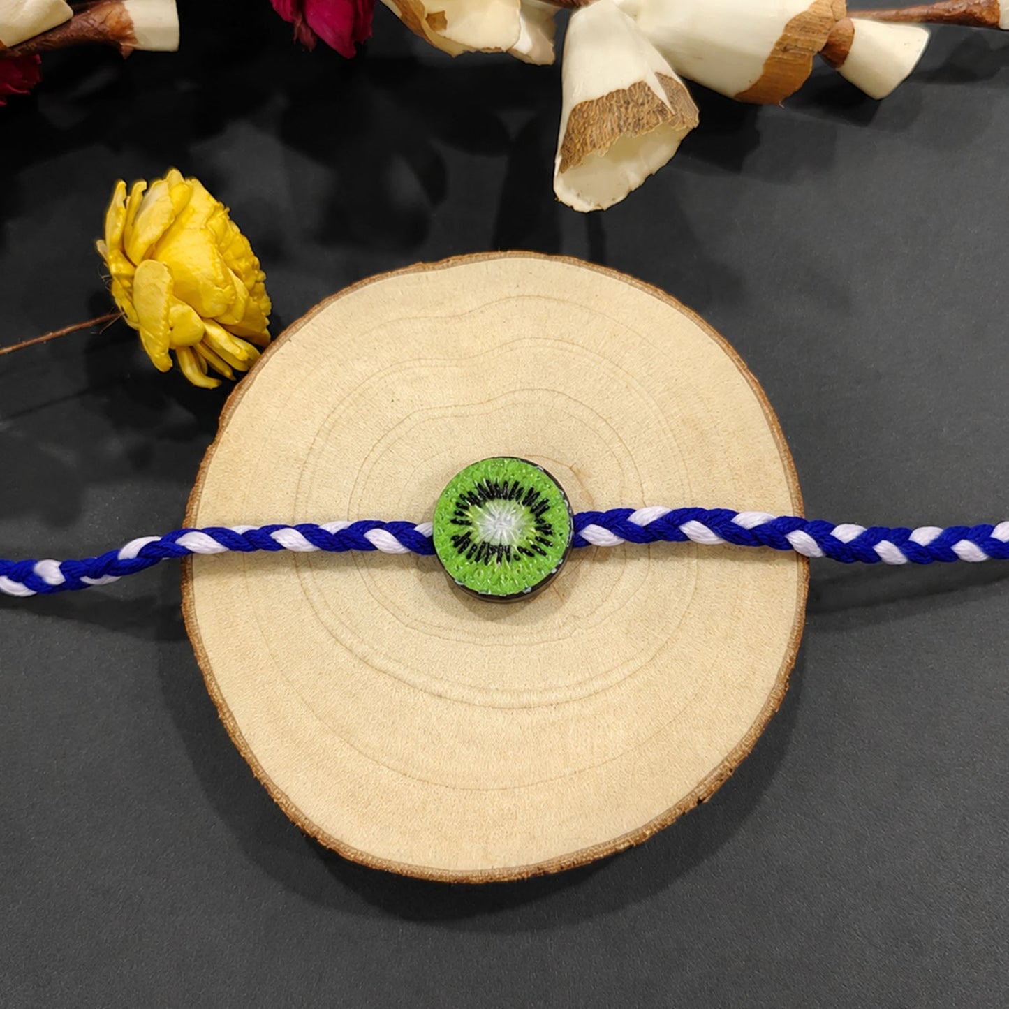 Side view of kiwi fruit charm rakhi with braided thread for Raksha Bandhan