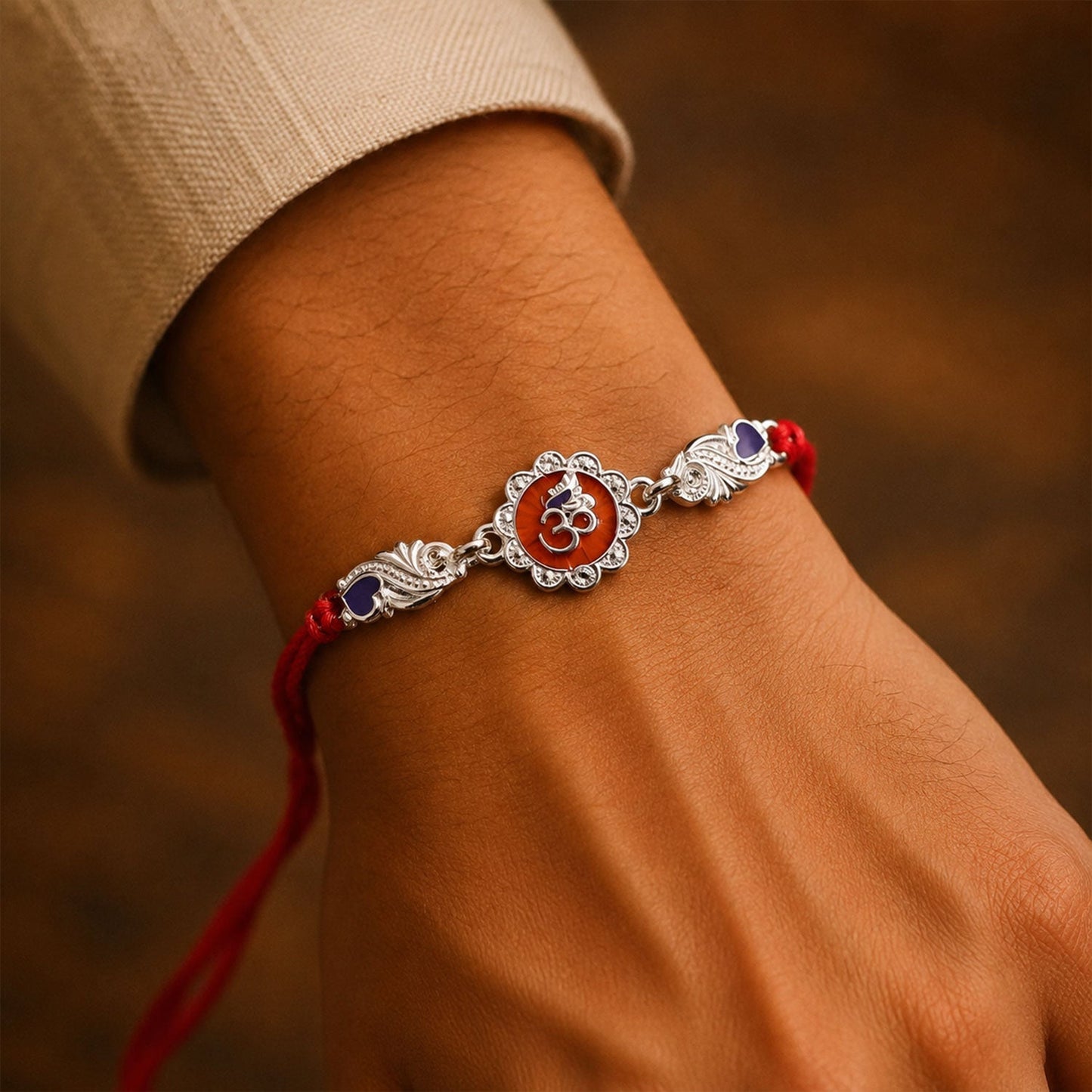 Close-up of silver Om floral Rakhi charm with dori thread