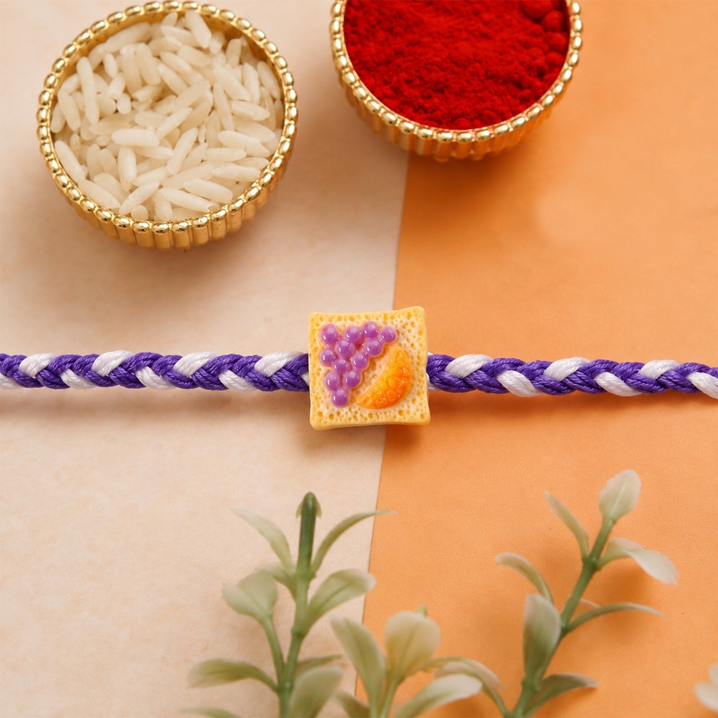 Close-up of cute Fruit Toast Charm on braided Rakhi thread