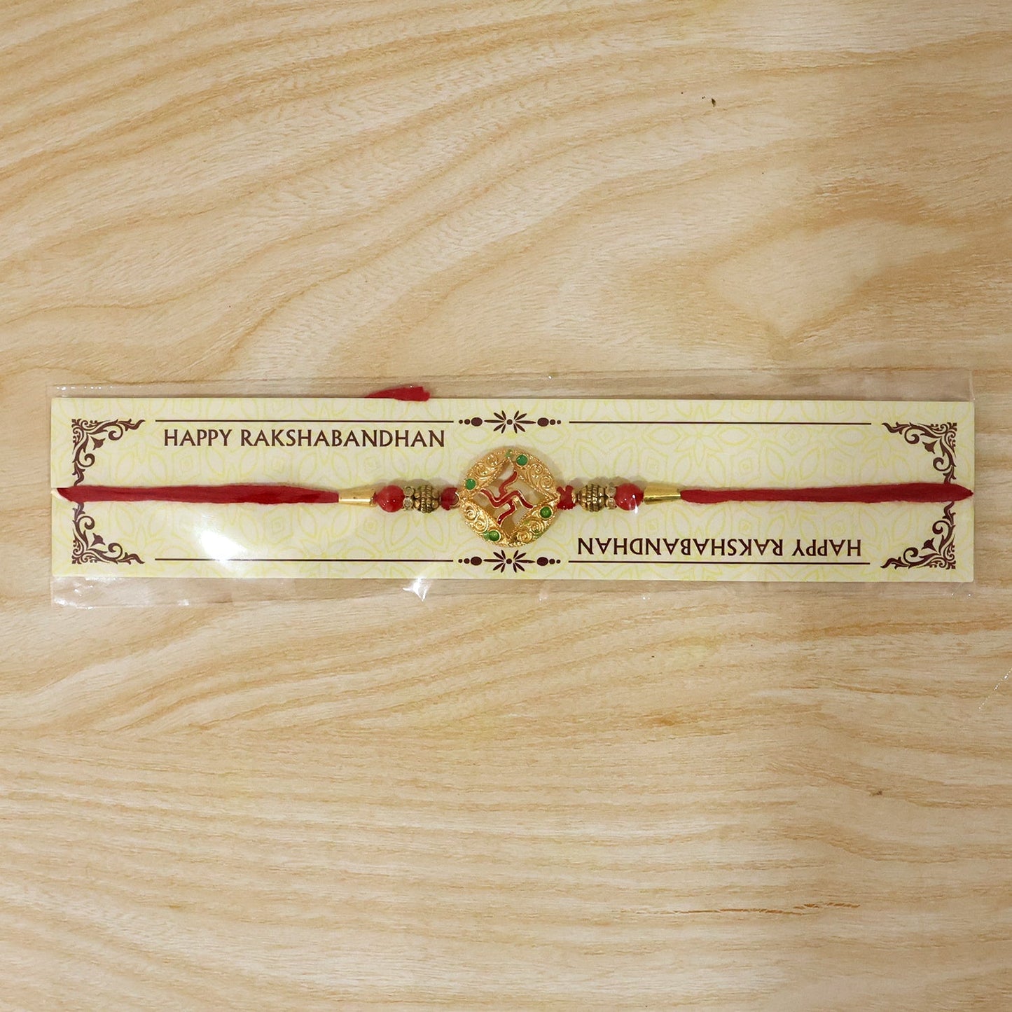 Festive golden Swastik designer Rakhi with beads on white background
