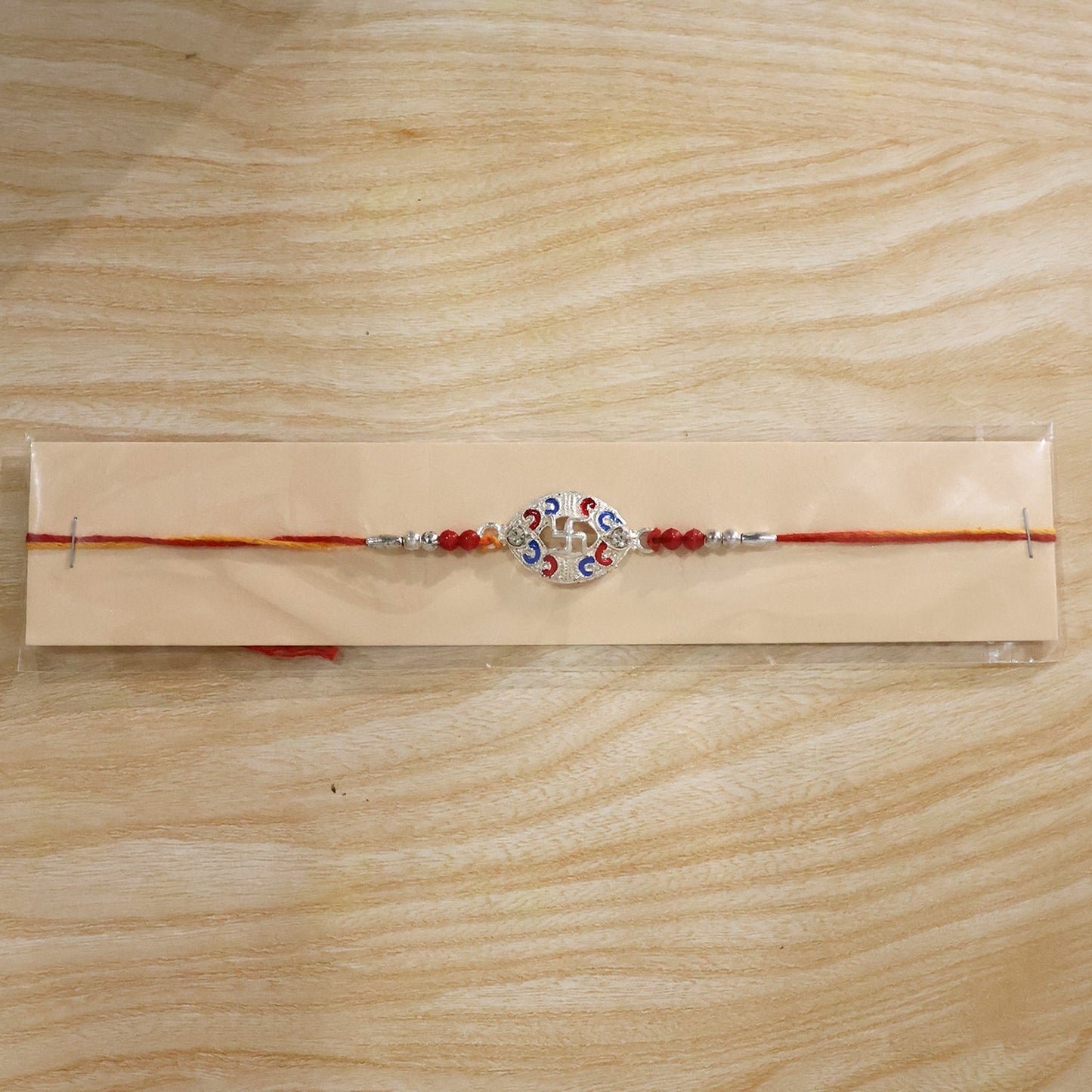 Beads of Silver Swastik Meena Oval Charm Rakhi on festive background