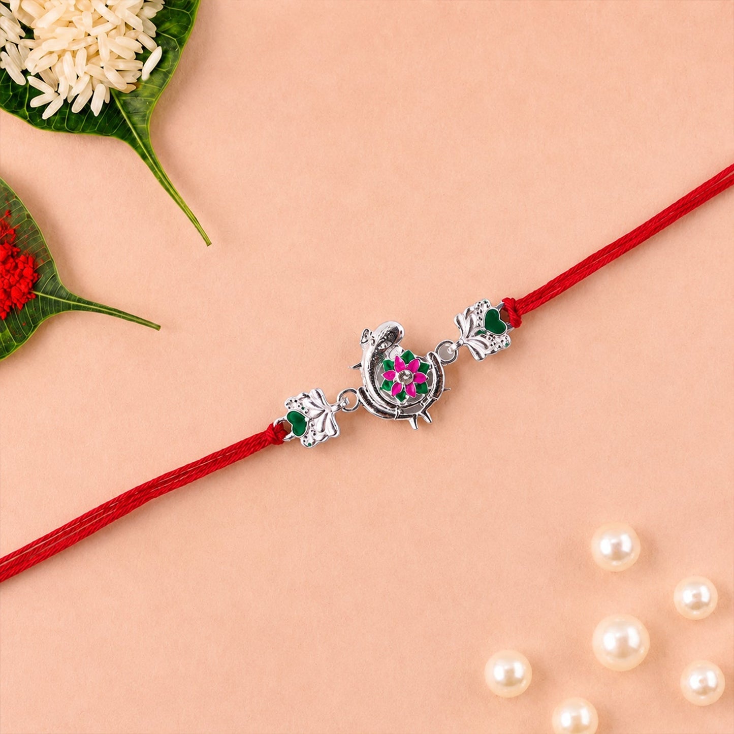 Side view of Silver Peacock Flower Heart Rakhi with dori