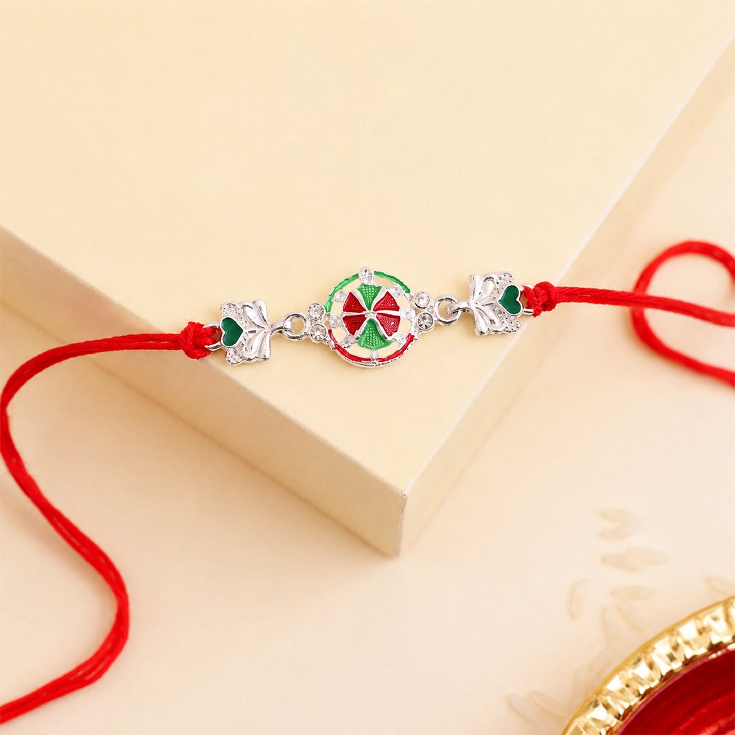 Top view of silver pinwheel heart rakhi on white background