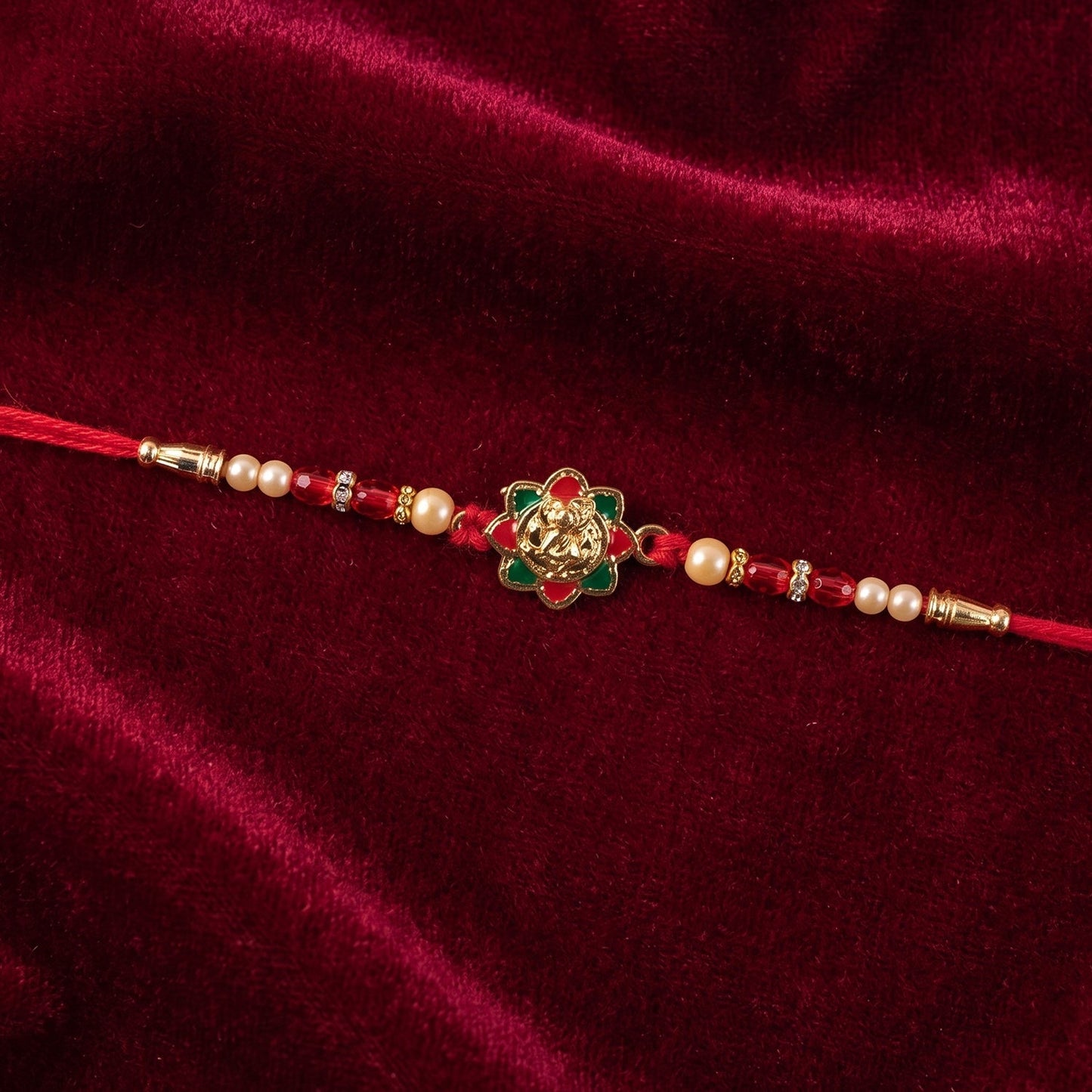 Premium festive rakhi with meenakari detailing, pearls, and red accents