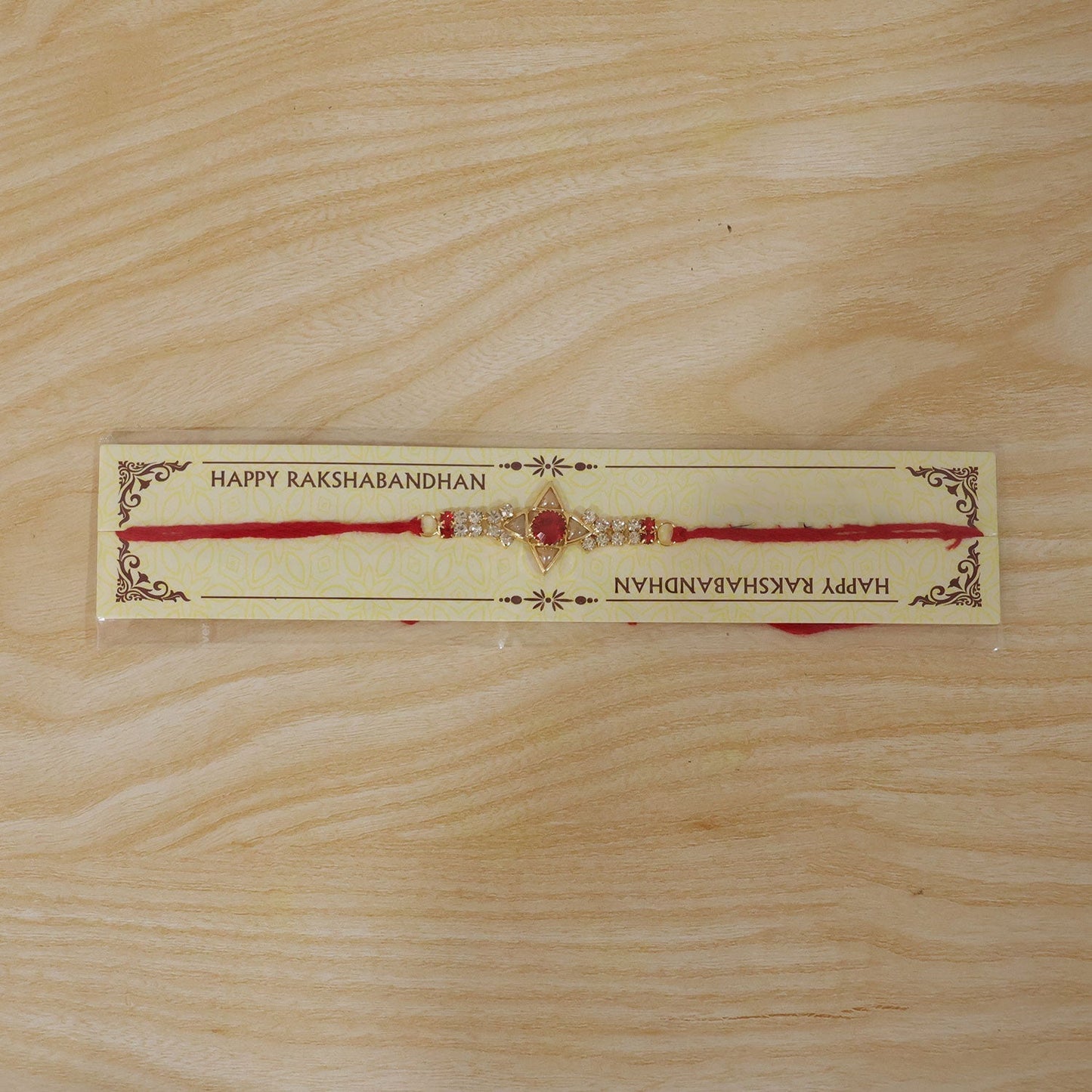 Traditional rakhi with modern sparkle, white and red stones on a gold star base