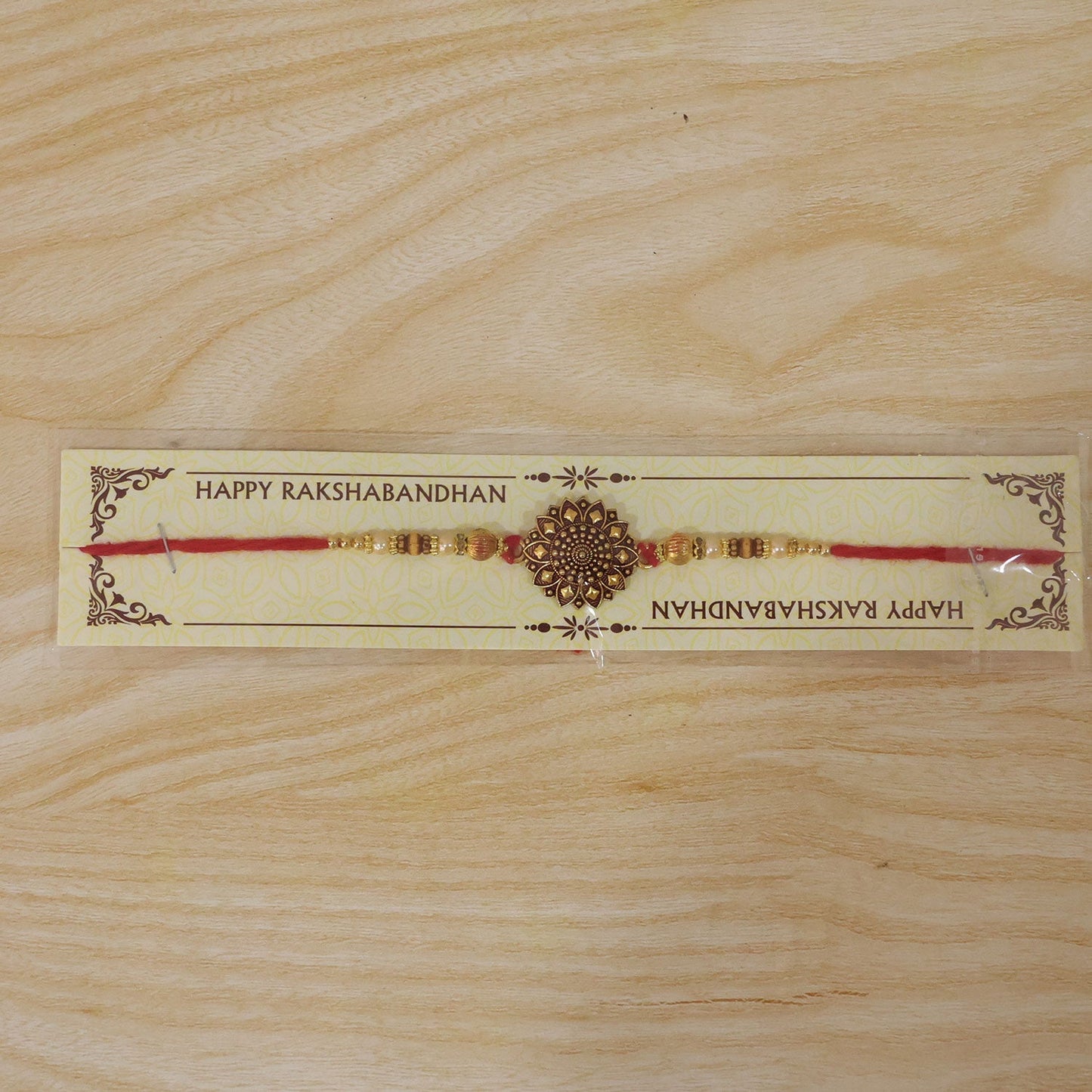 Top-down view of antique gold floral mandala Rakhi on white background