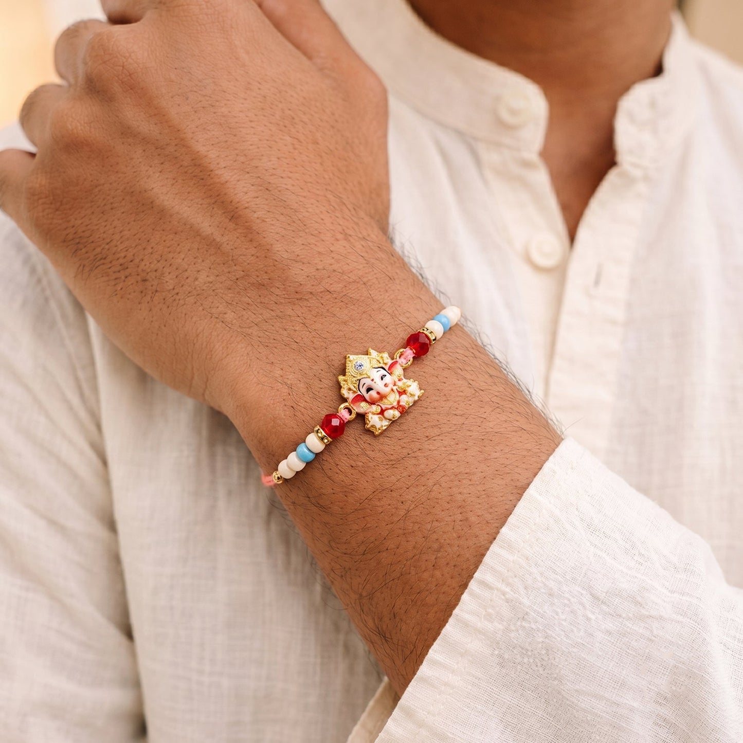 Elegant Ganesha Rakhi with intricate golden design and vibrant beads on display.