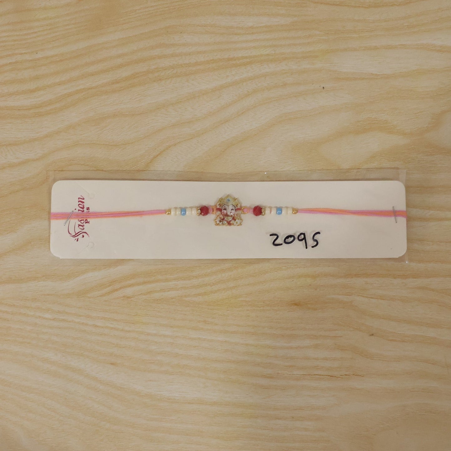 Complete view of the Ganesha Rakhi with colourful accents and packaging.