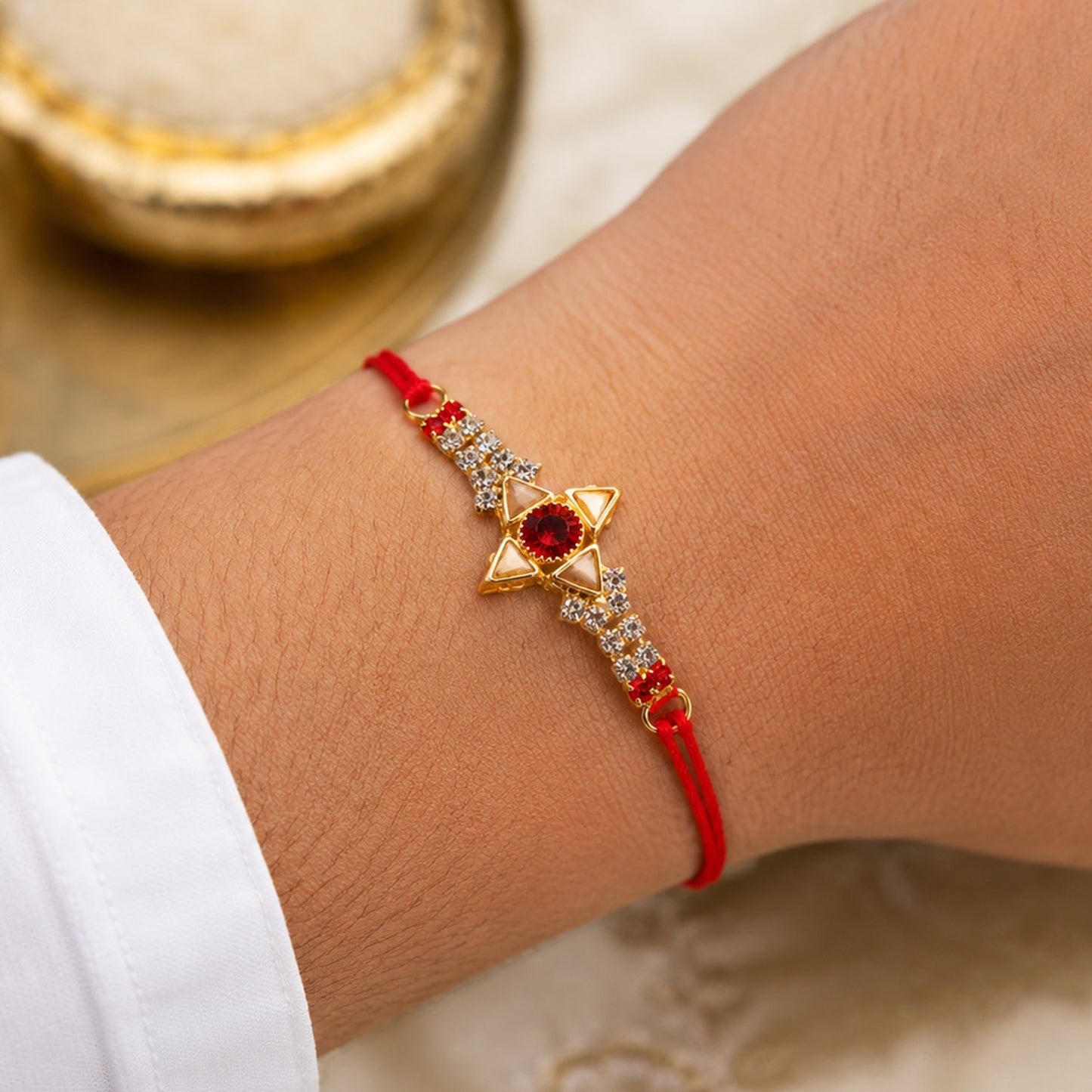 Close-up of red AD stone and gold marquise design on the Rakhi.