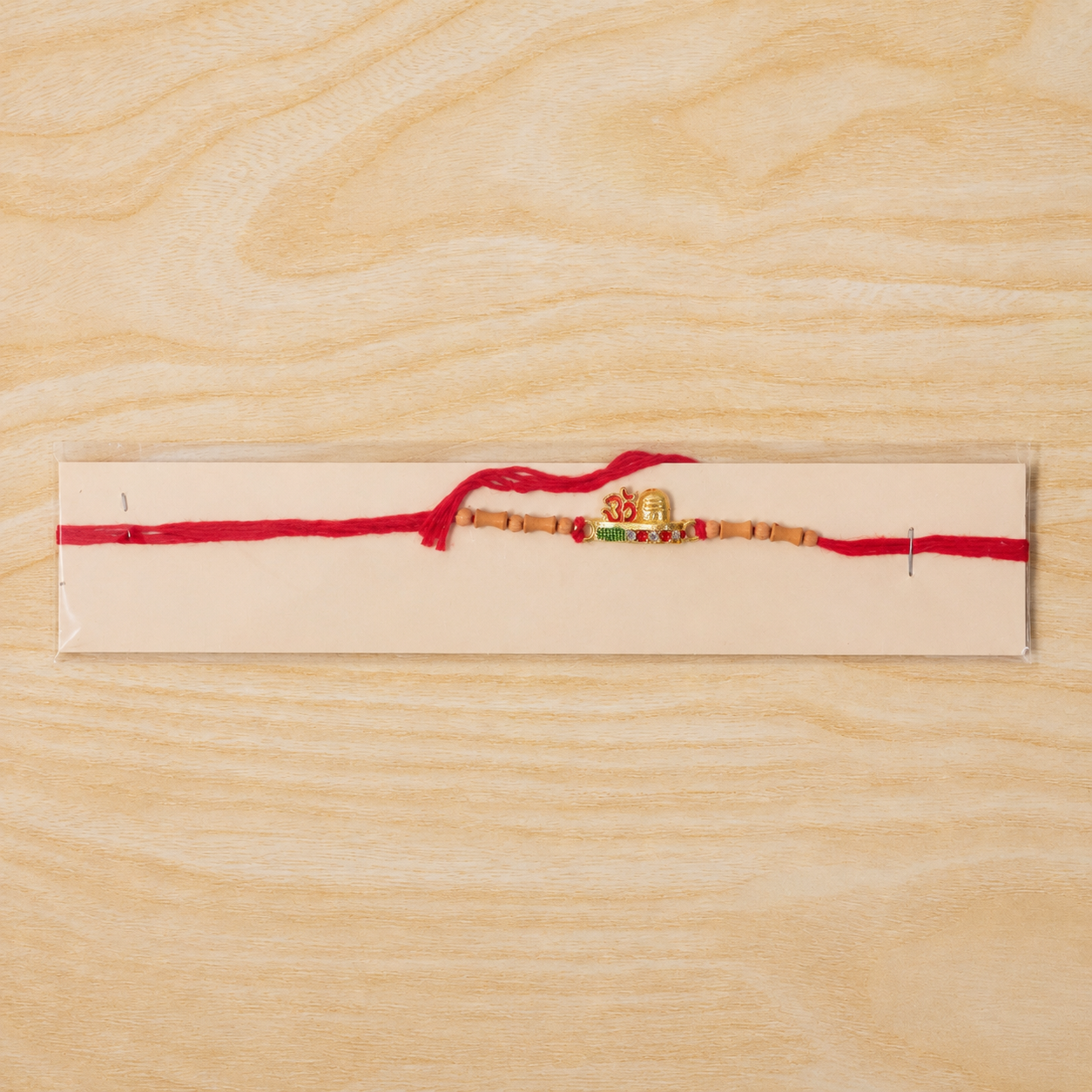 Full front view of the stylish Om Rakhi with golden Om and decorative beads.