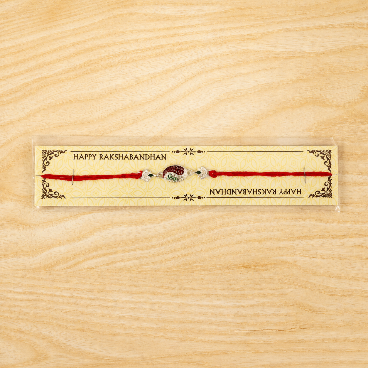 Front view of the silver oval Meenakari Rakhi with inscriptions.
