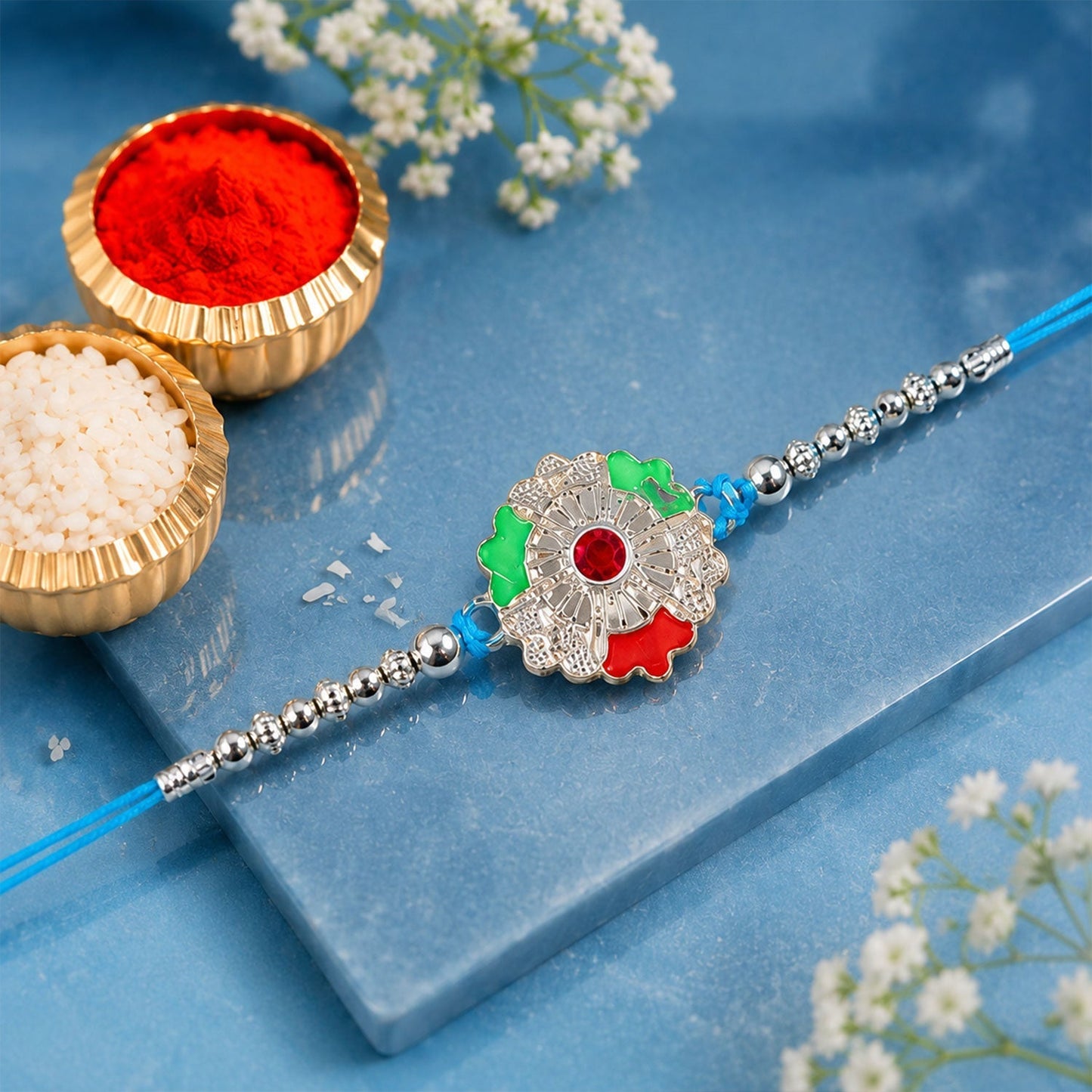 Close-up of silver meenakari floral Rakhi with beads for siblings