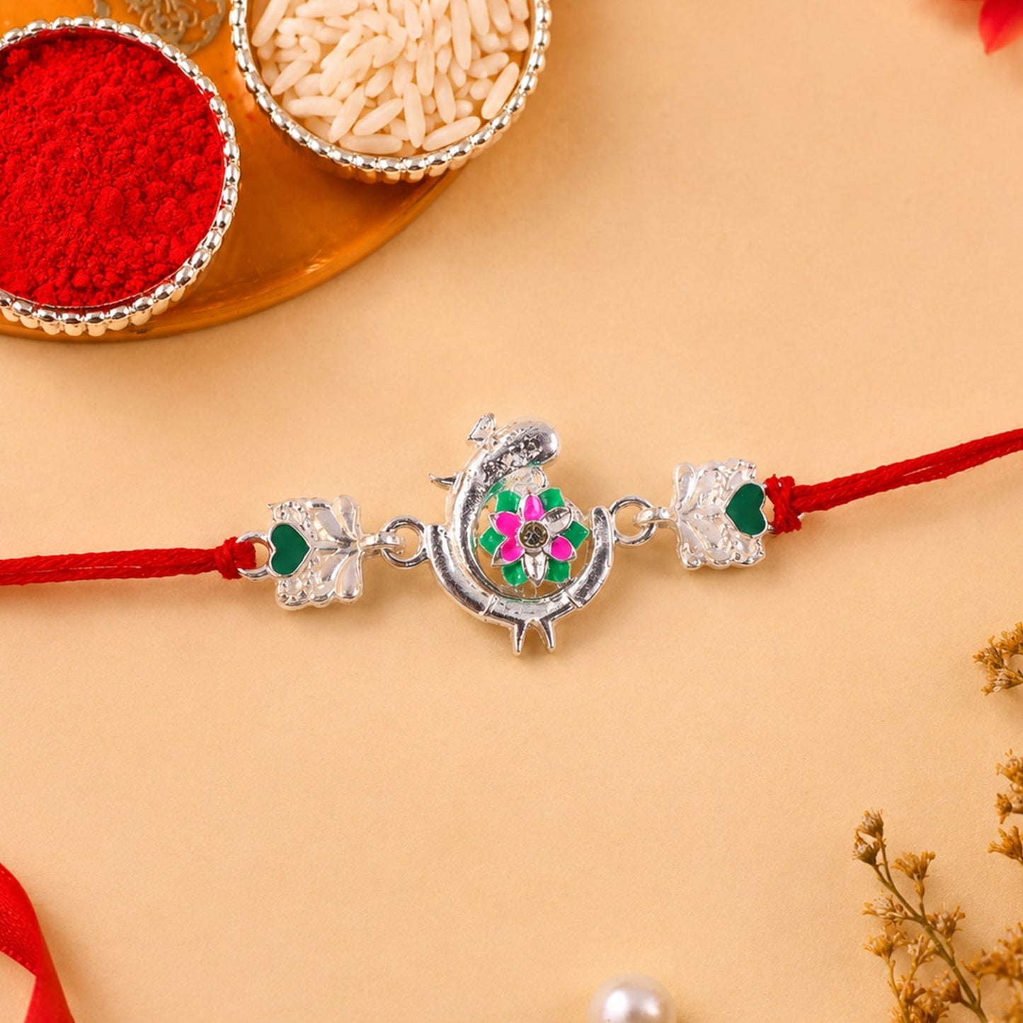 Festive silver peacock rakhi with pink and green enamel accents