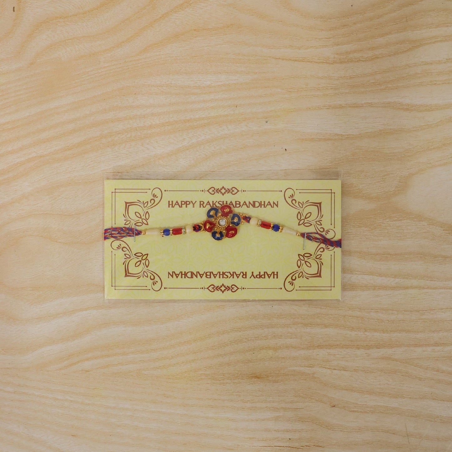 Detailed close-up of pearl bead Rakhi with meenakari floral motif