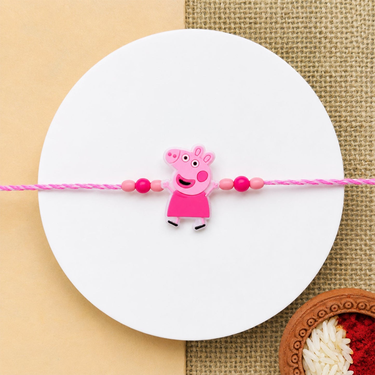 Cartoon rakhi with pink beads displayed on a white background, cheerful design