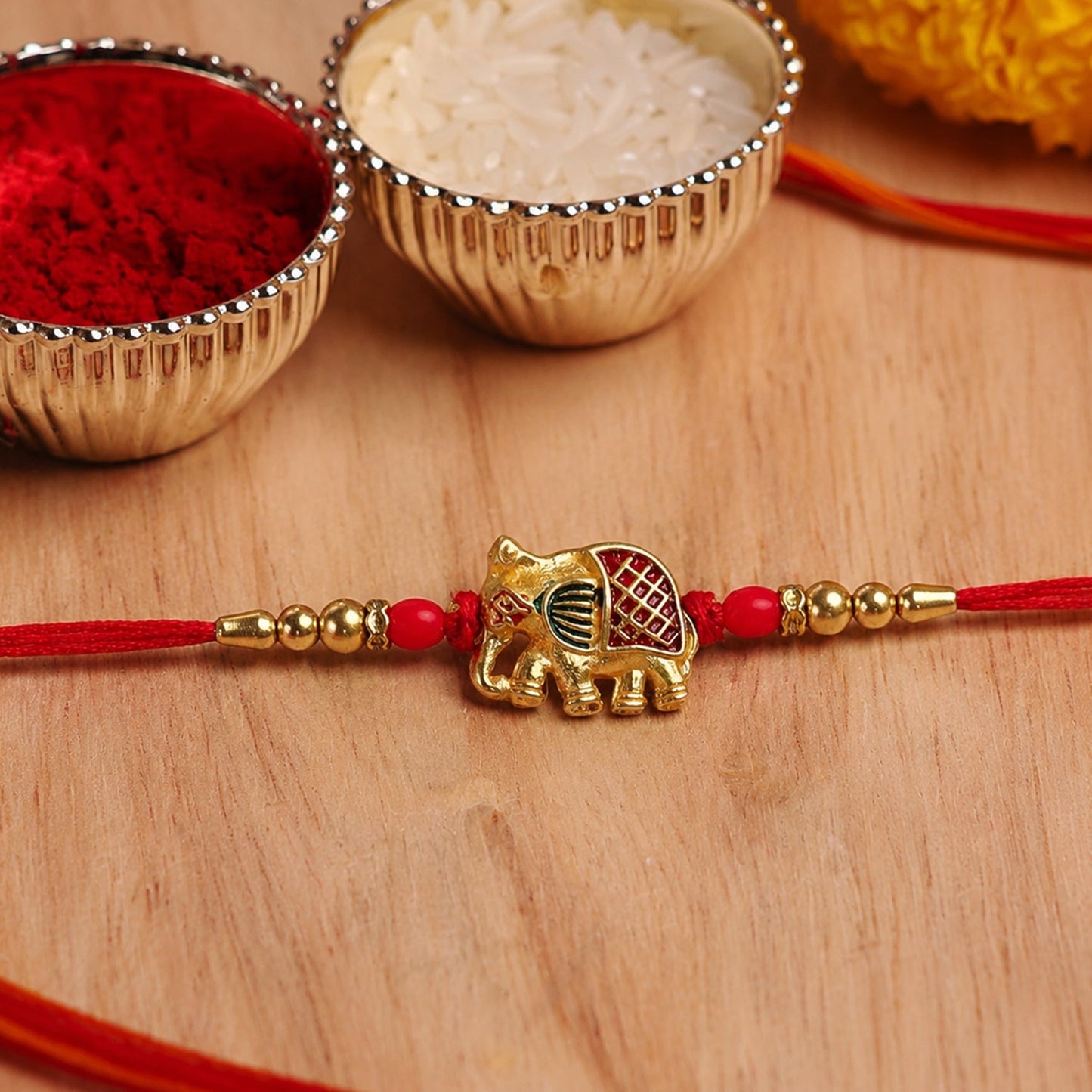 Close-up of Gold Elephant Charm with decorative beads on Rakhi