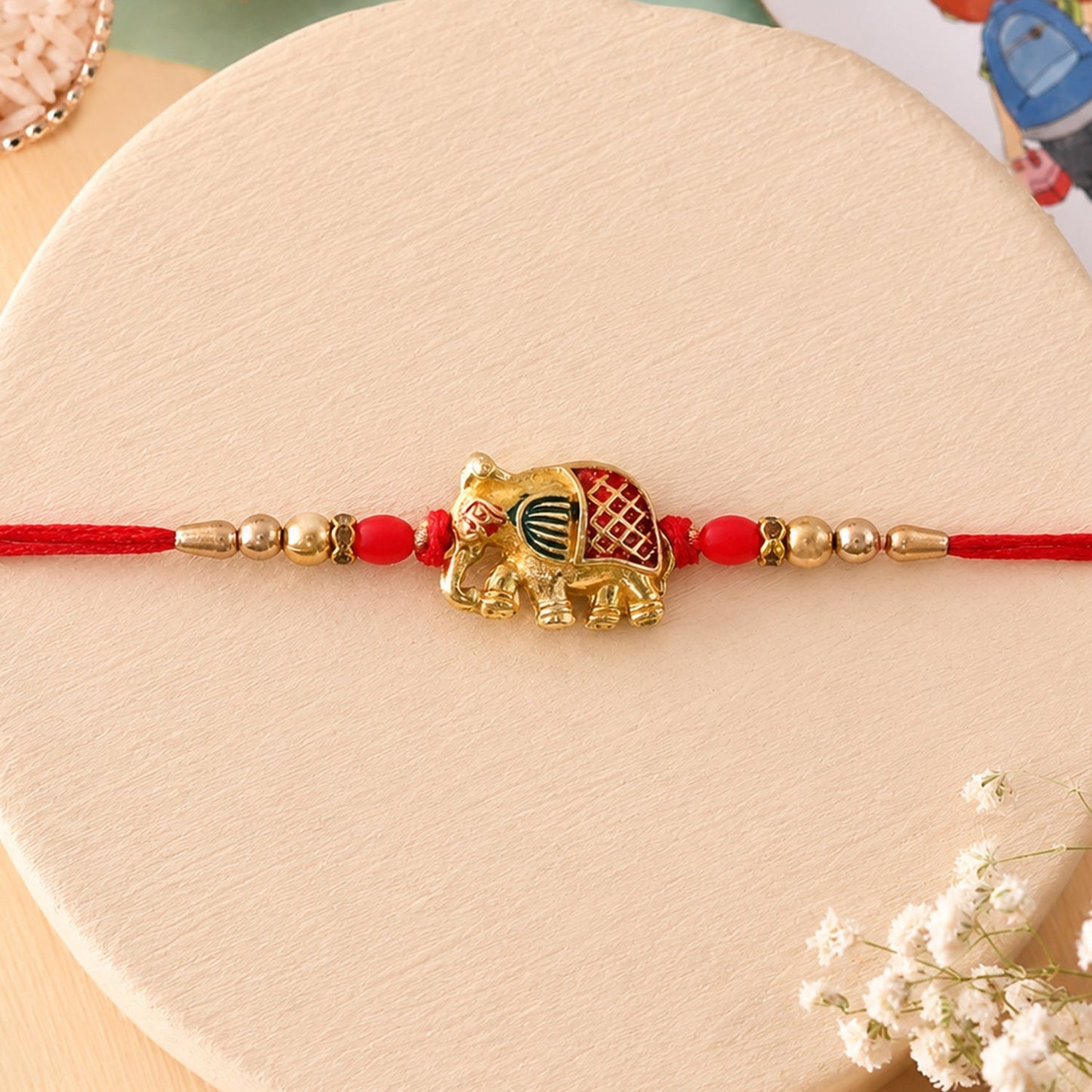 Detailed view of Gold Elephant Charm with beads on Rakhi