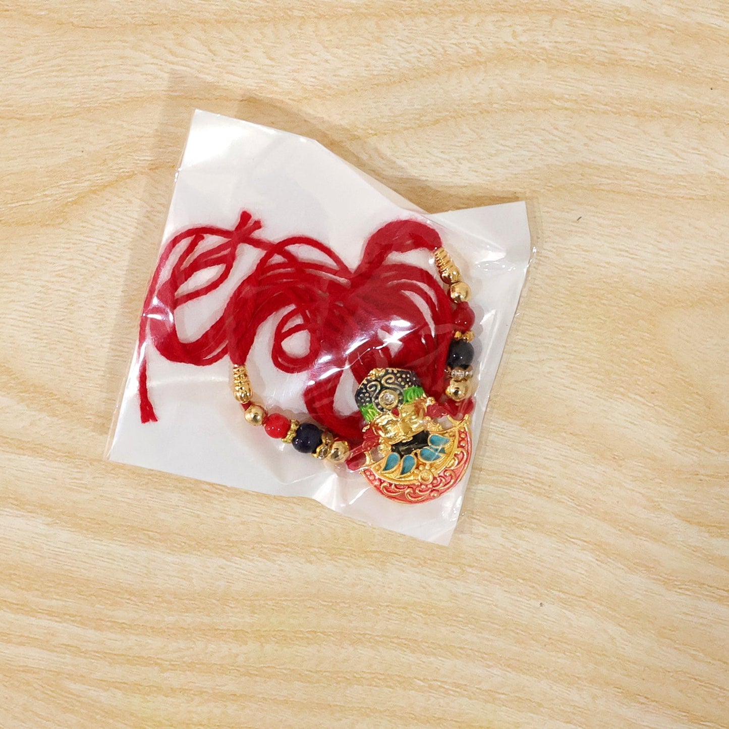 Stylish multicolor enamel rakhi with traditional religious design, ideal for brothers of all ages
