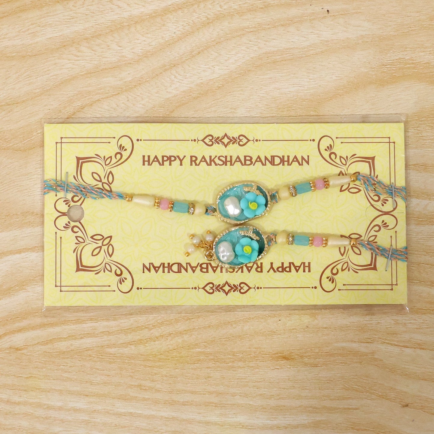 Festive Aqua Floral Pearl Lumba Rakhi sitting elegantly on a surface
