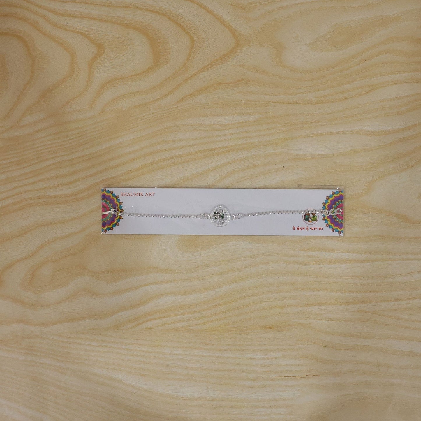 Close-up of silver enamel floral design Rakhi for brother