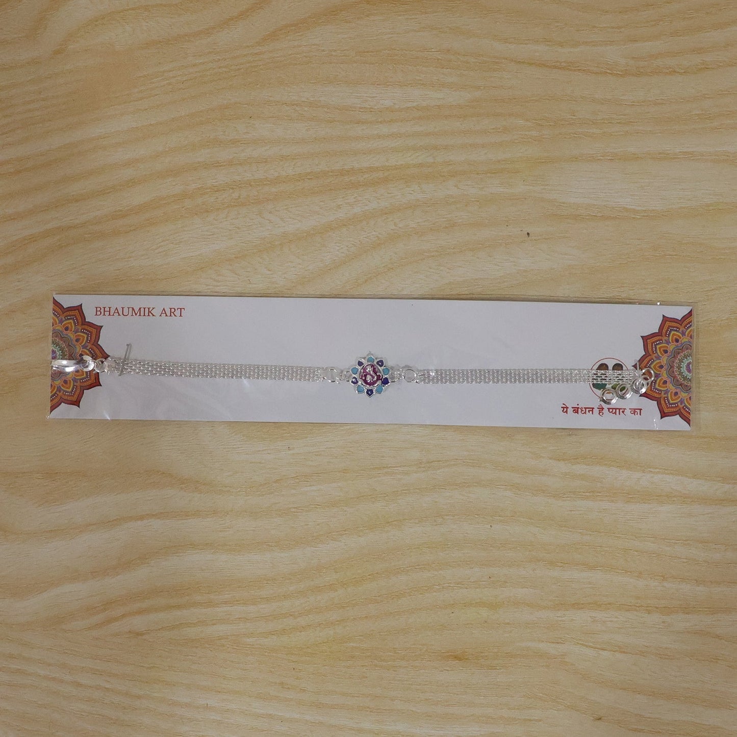 Vibrant floral Rakhi with enamel Ganesha charm, suitable for all ages